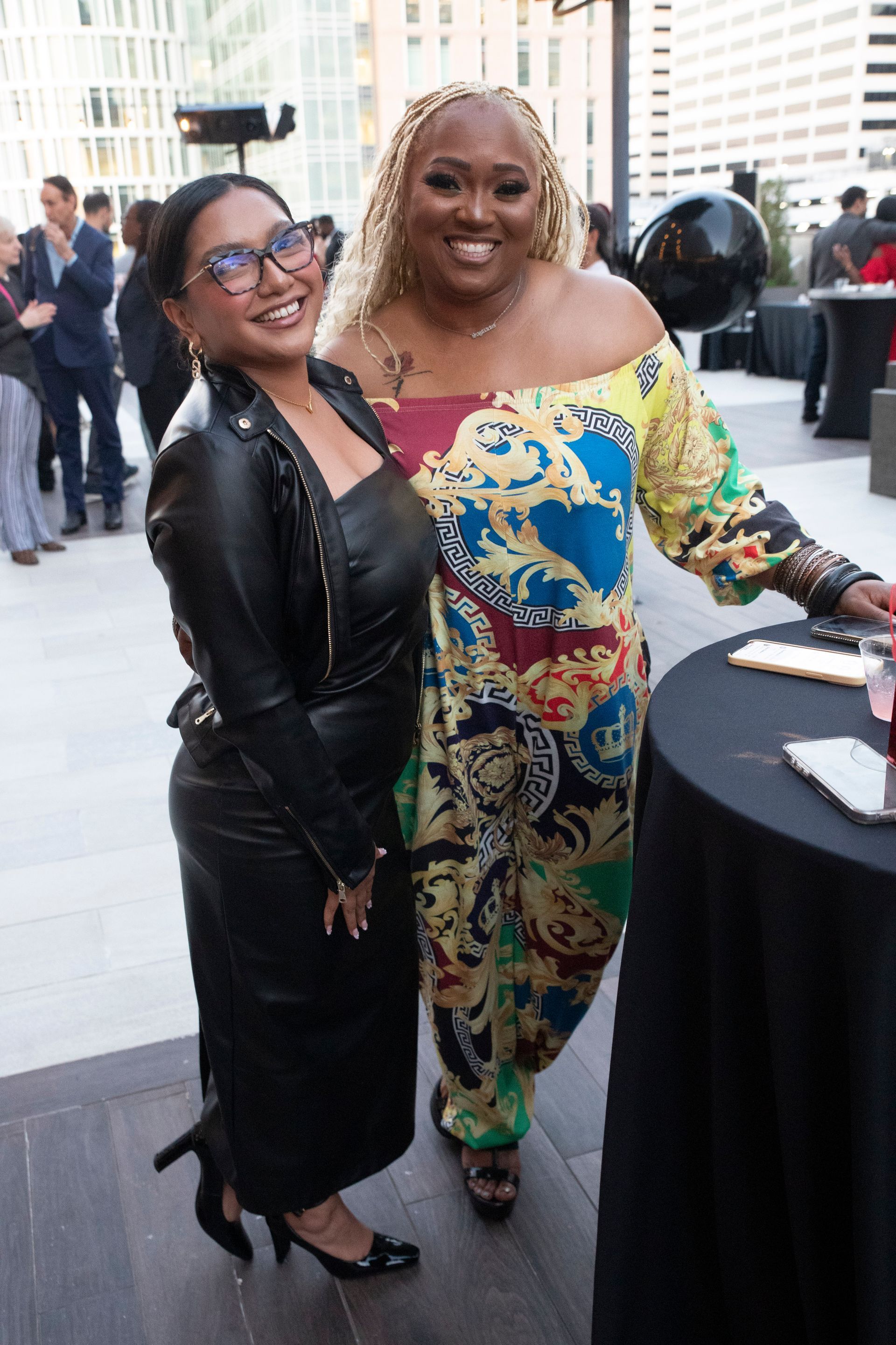 Two women are posing for a picture in front of a table.