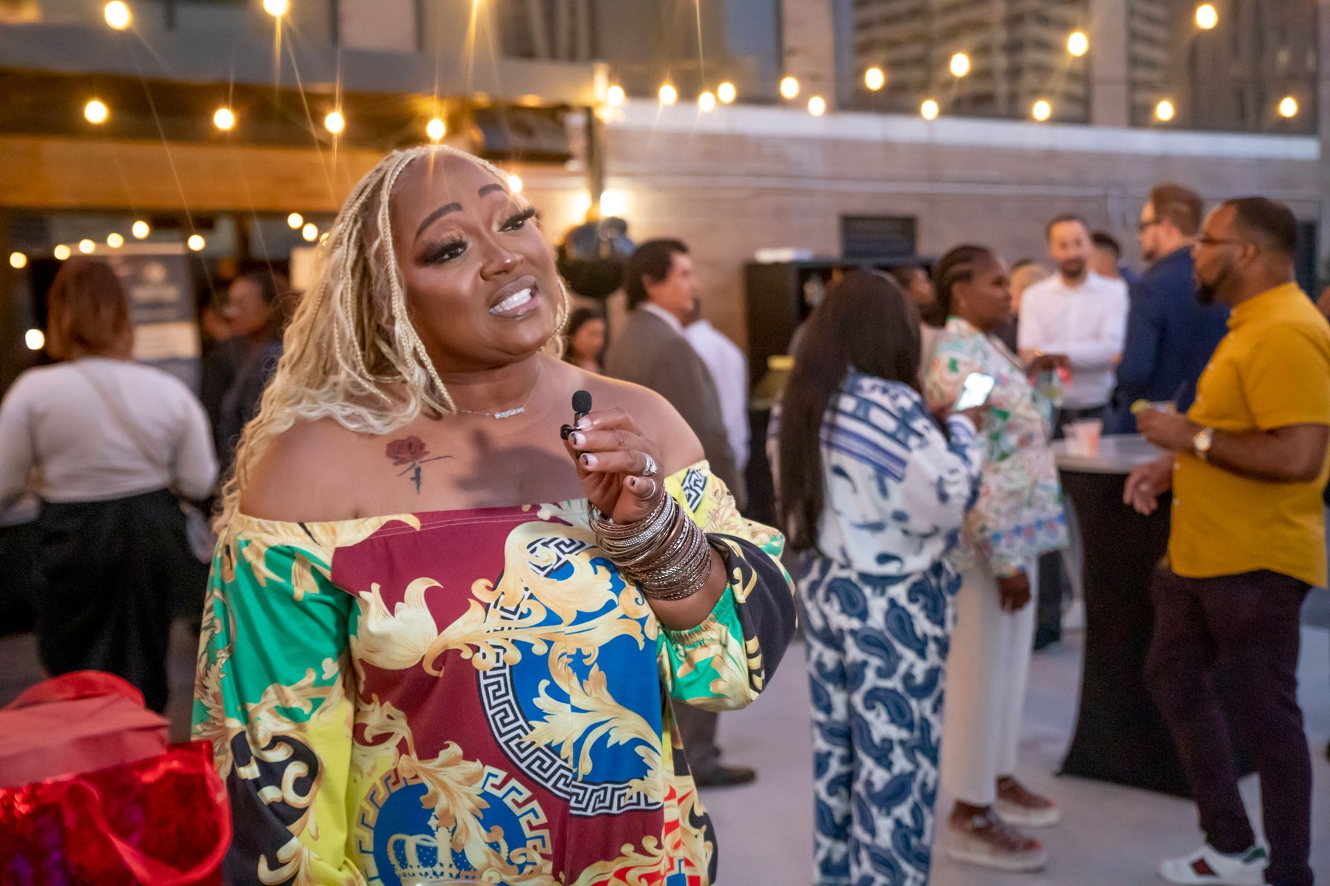 A woman is standing in front of a crowd of people holding a microphone.