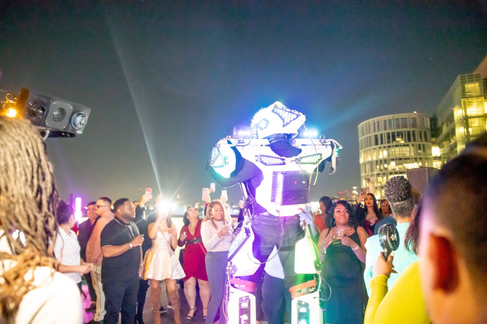 A group of people are dancing in front of a robot.