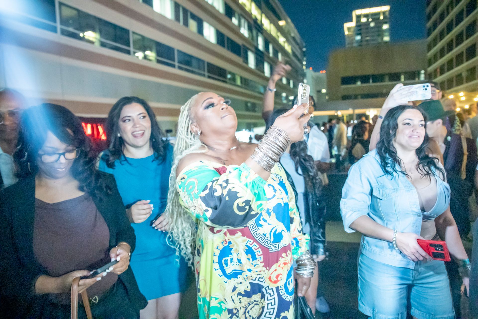 A woman is taking a picture of herself while standing in front of a crowd of people.