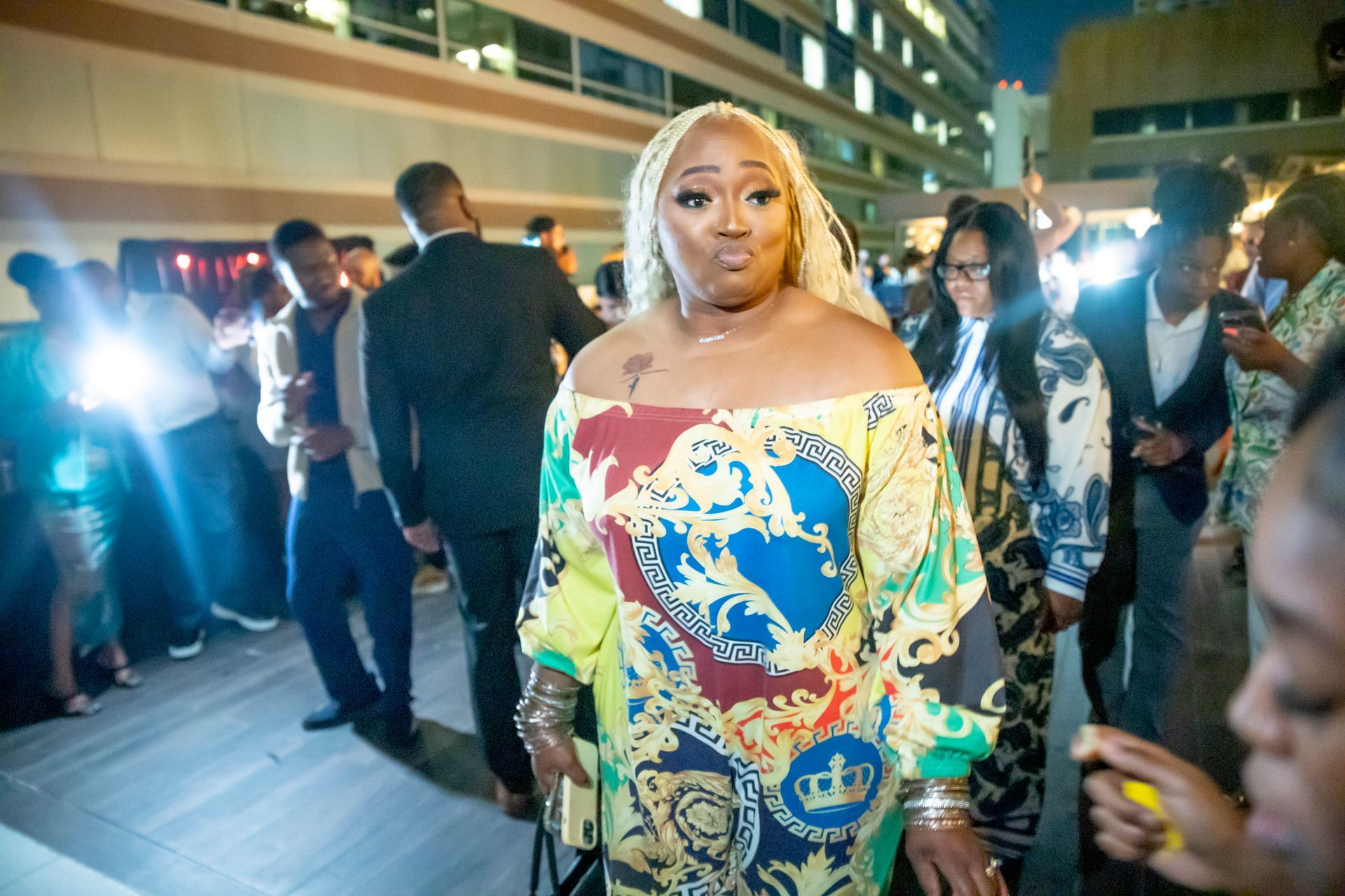 A woman in a colorful dress is standing in a crowd of people.