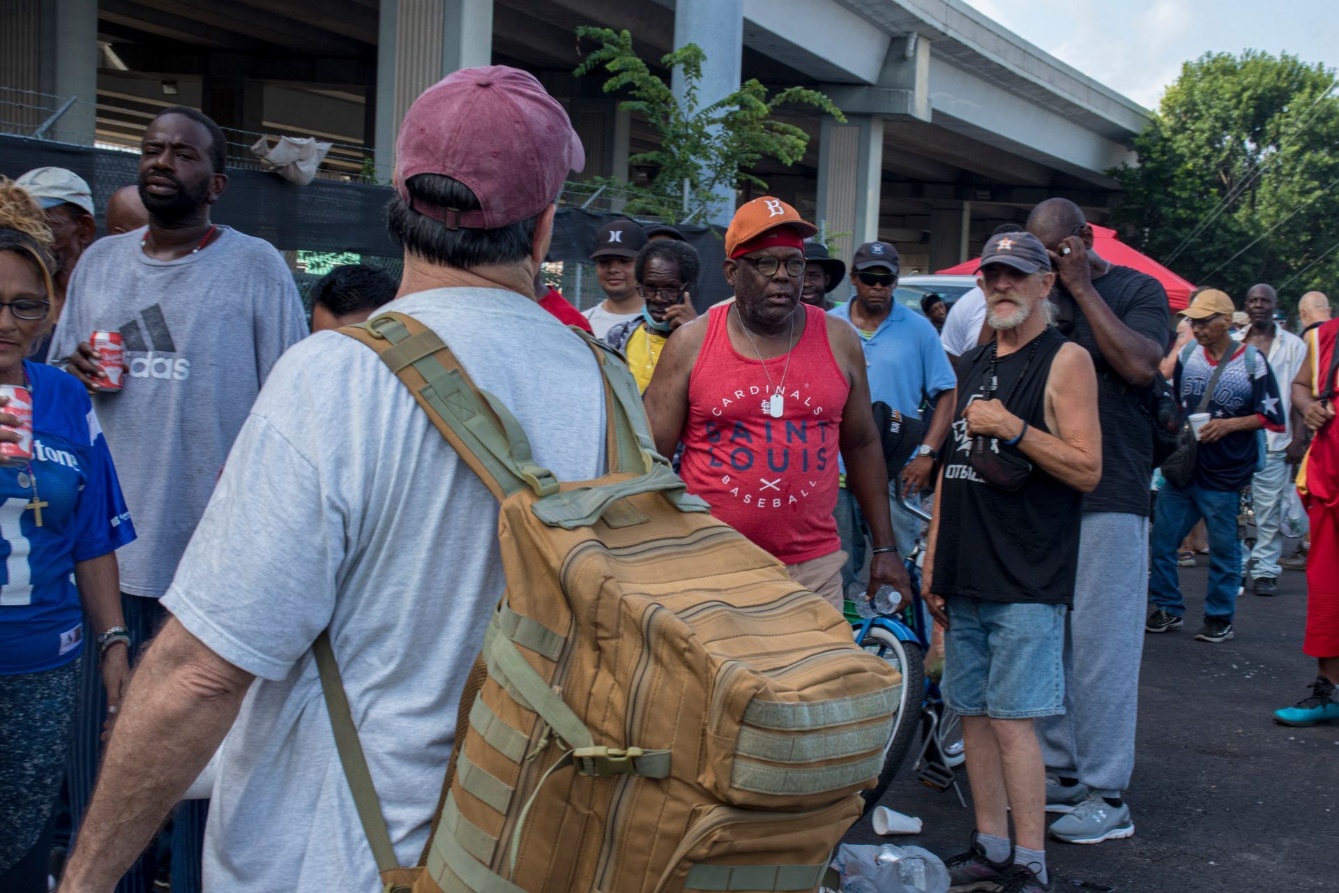 A man with a backpack is standing in a crowd of people.