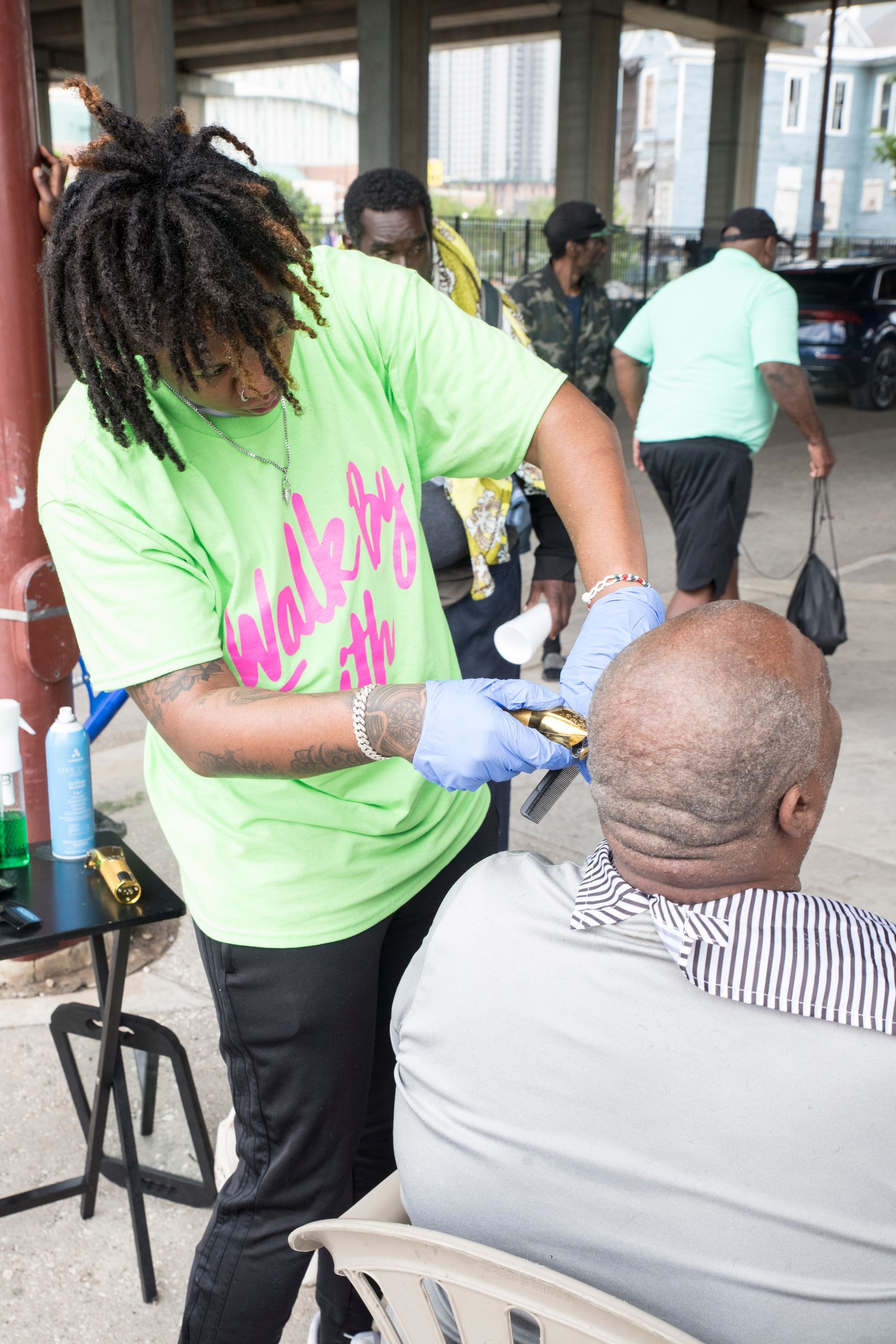 A man is getting his hair cut by a woman in a green shirt.