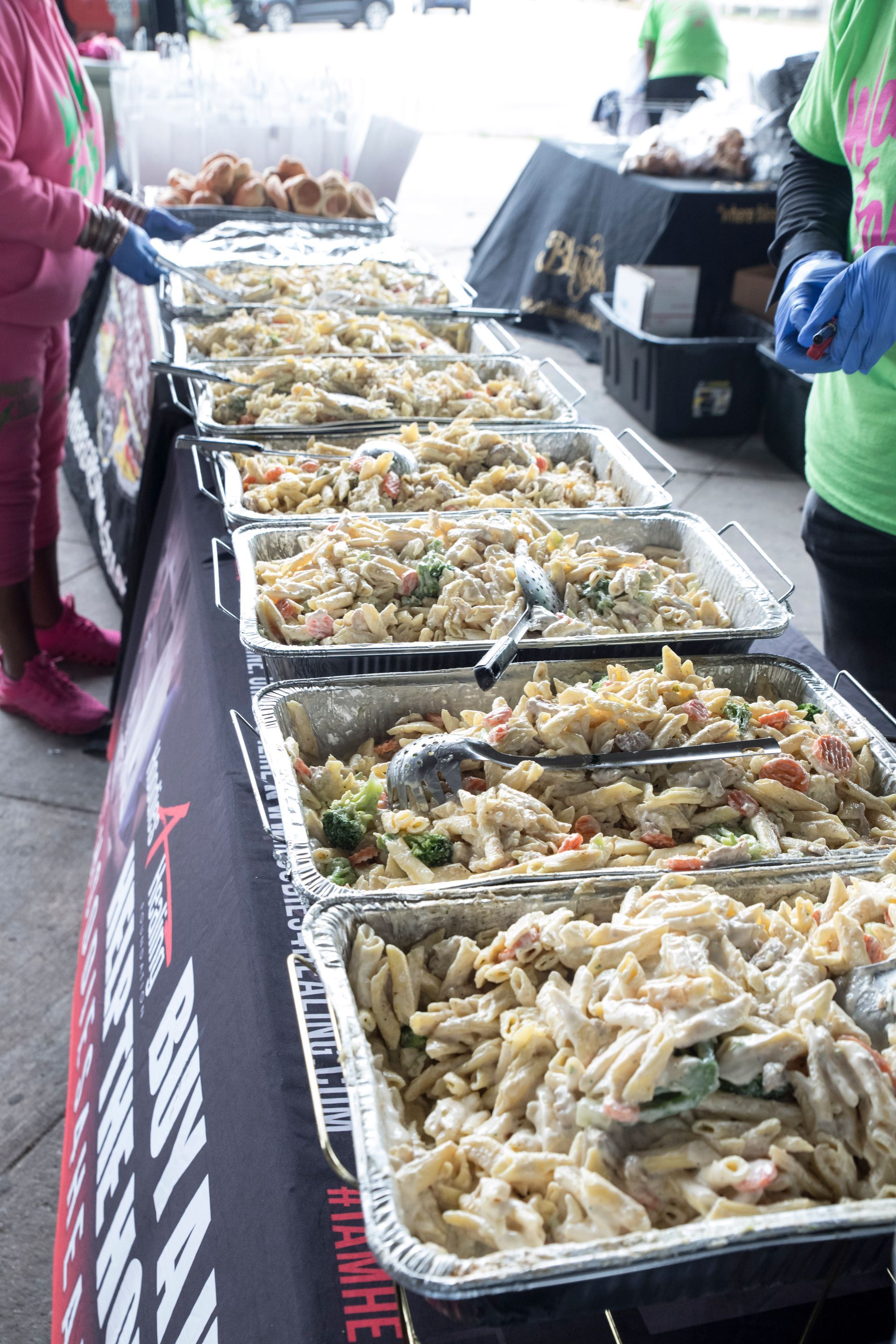 A row of trays filled with pasta and vegetables on a table.