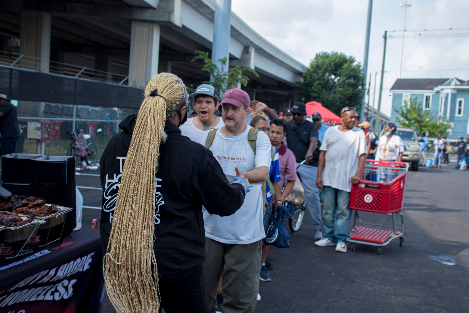A woman with braids is talking to a group of people in a parking lot.