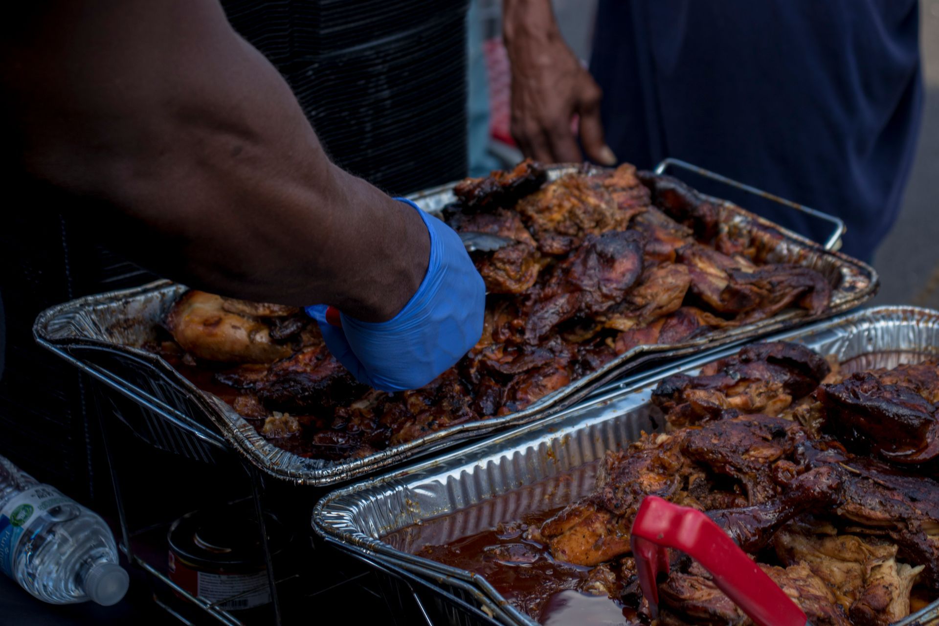 A person is holding a tray of meat with tongs.