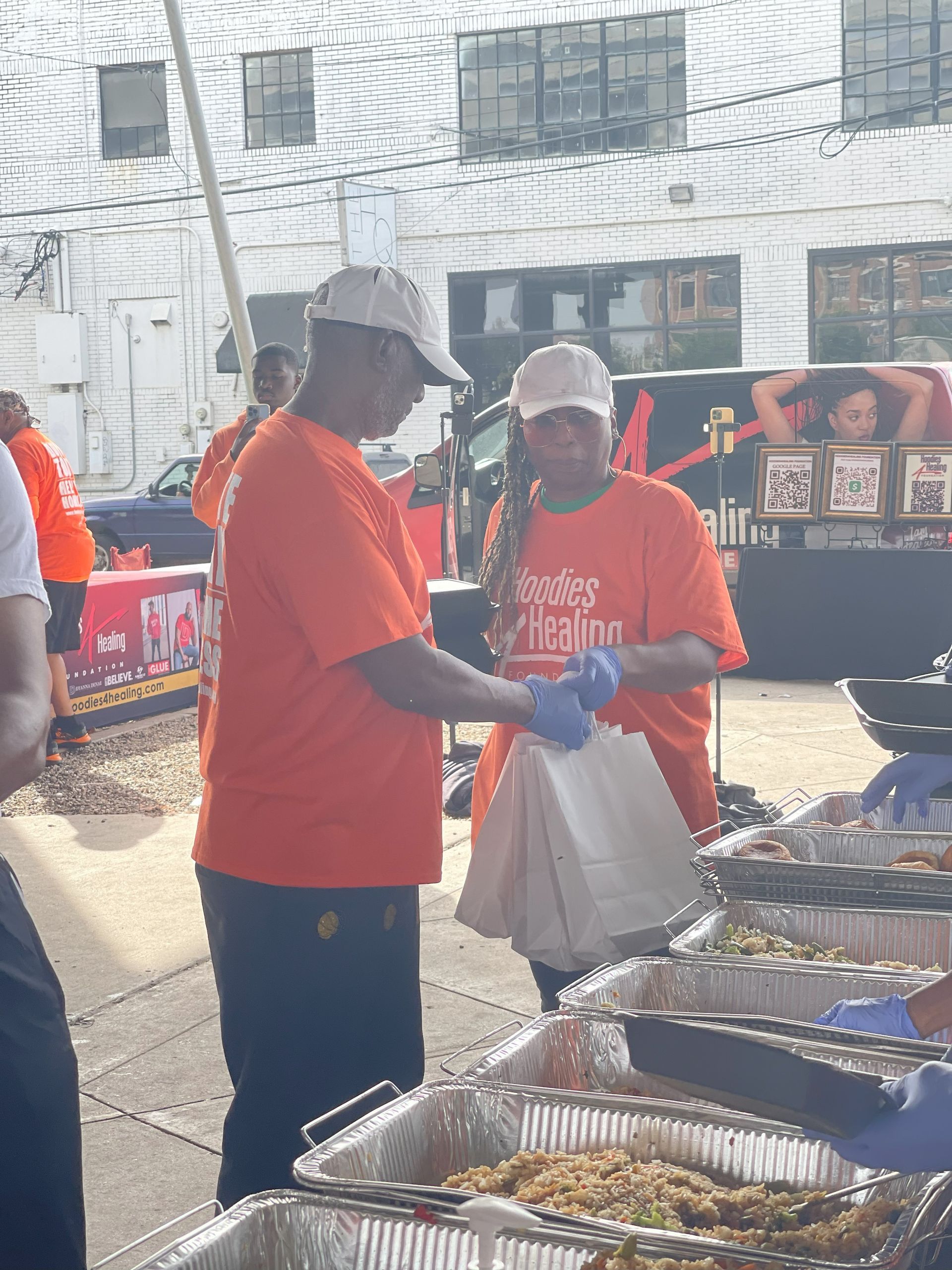 A man in an orange shirt is standing in front of a buffet line.