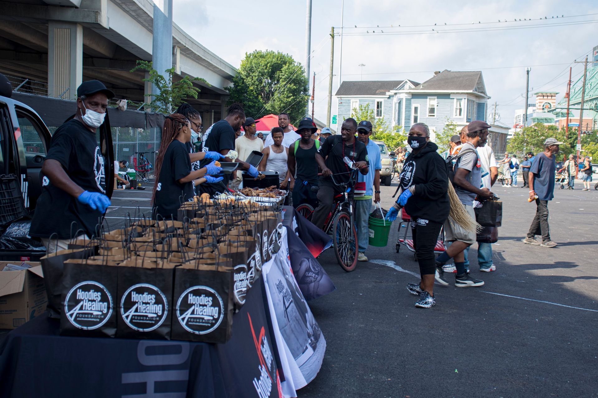 A group of people are standing around a table with boxes of food on it.