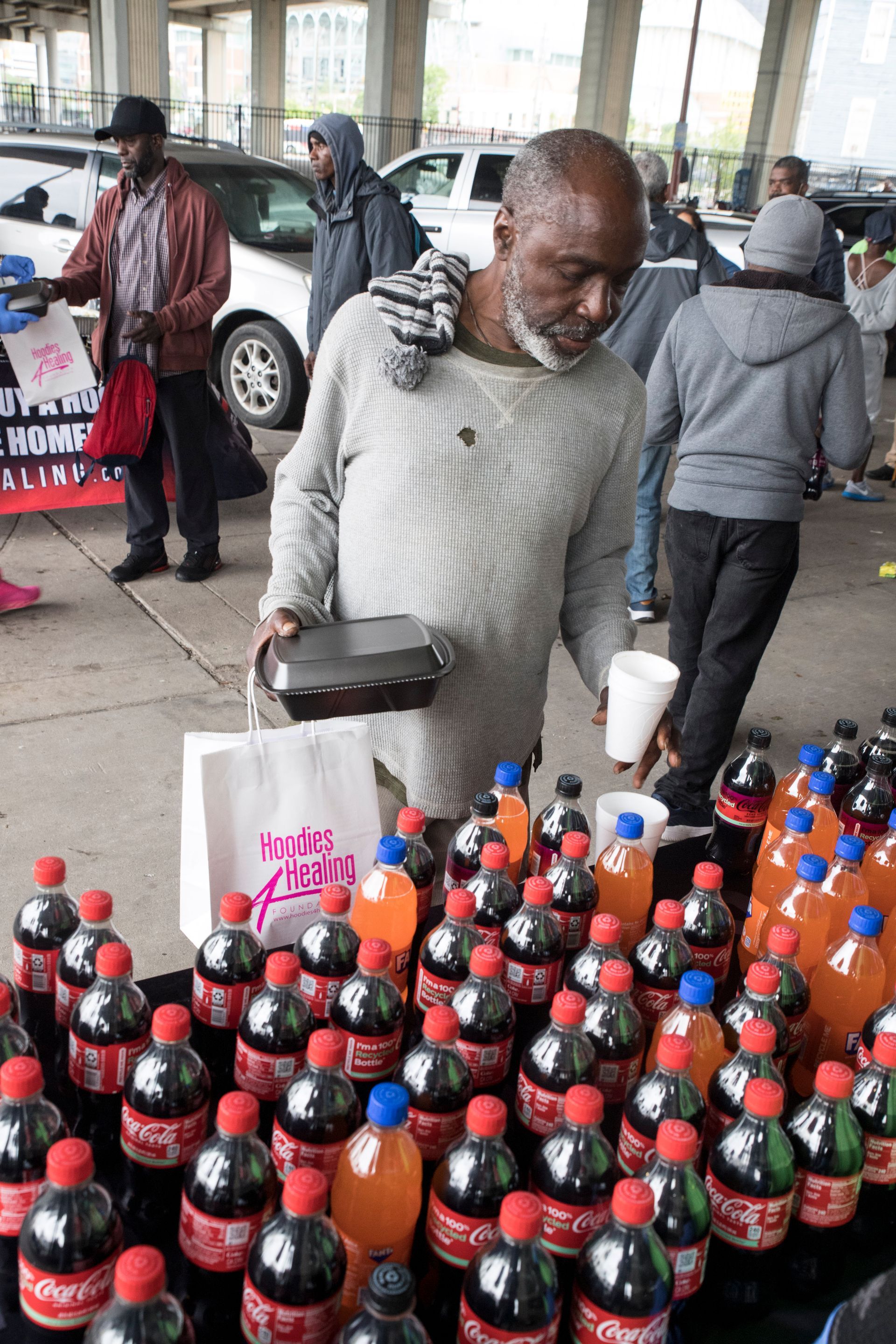 A man is standing in front of a table full of coca cola bottles.