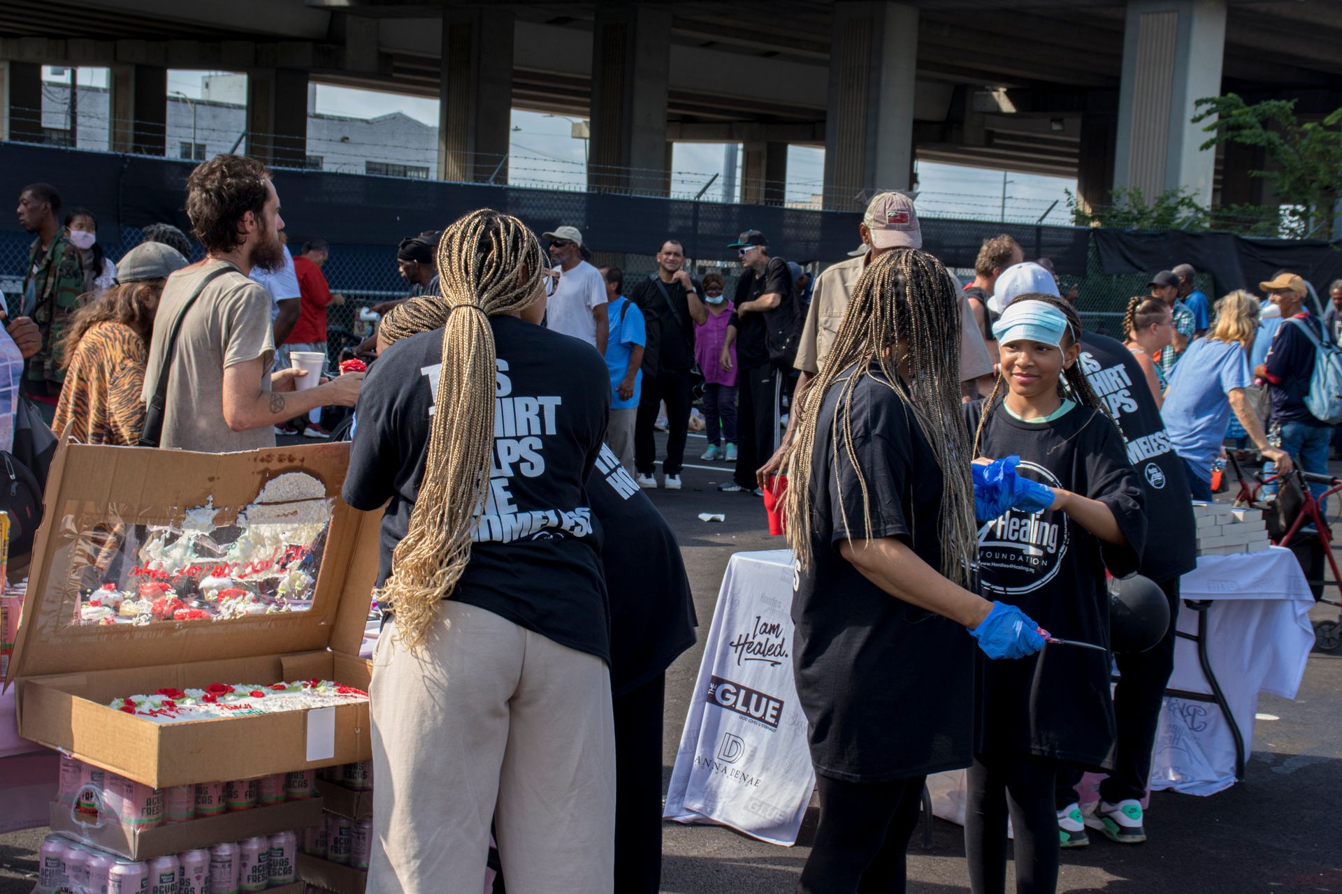 A group of people are standing around a table in a parking lot.