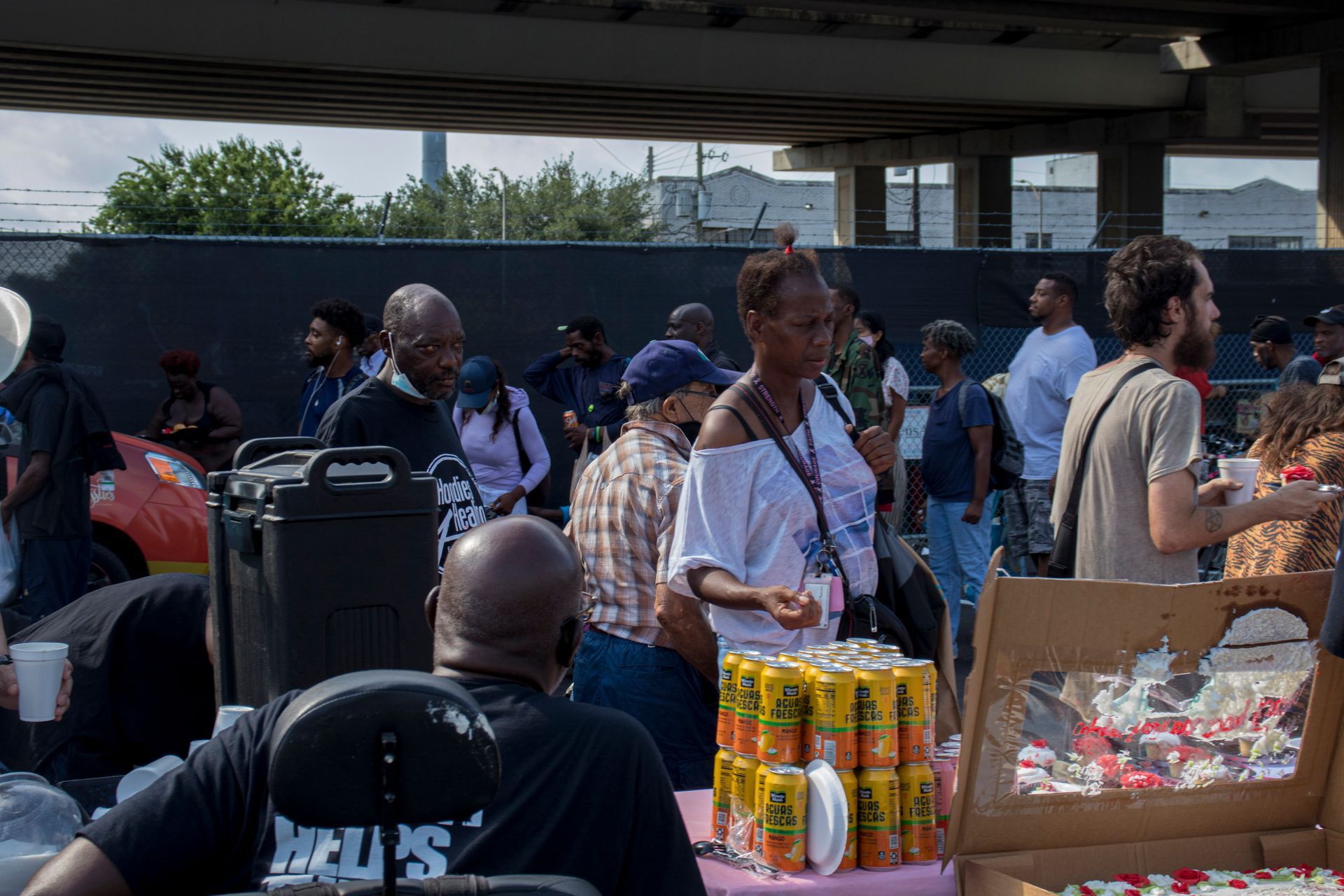 A group of people are standing around a table under a bridge.