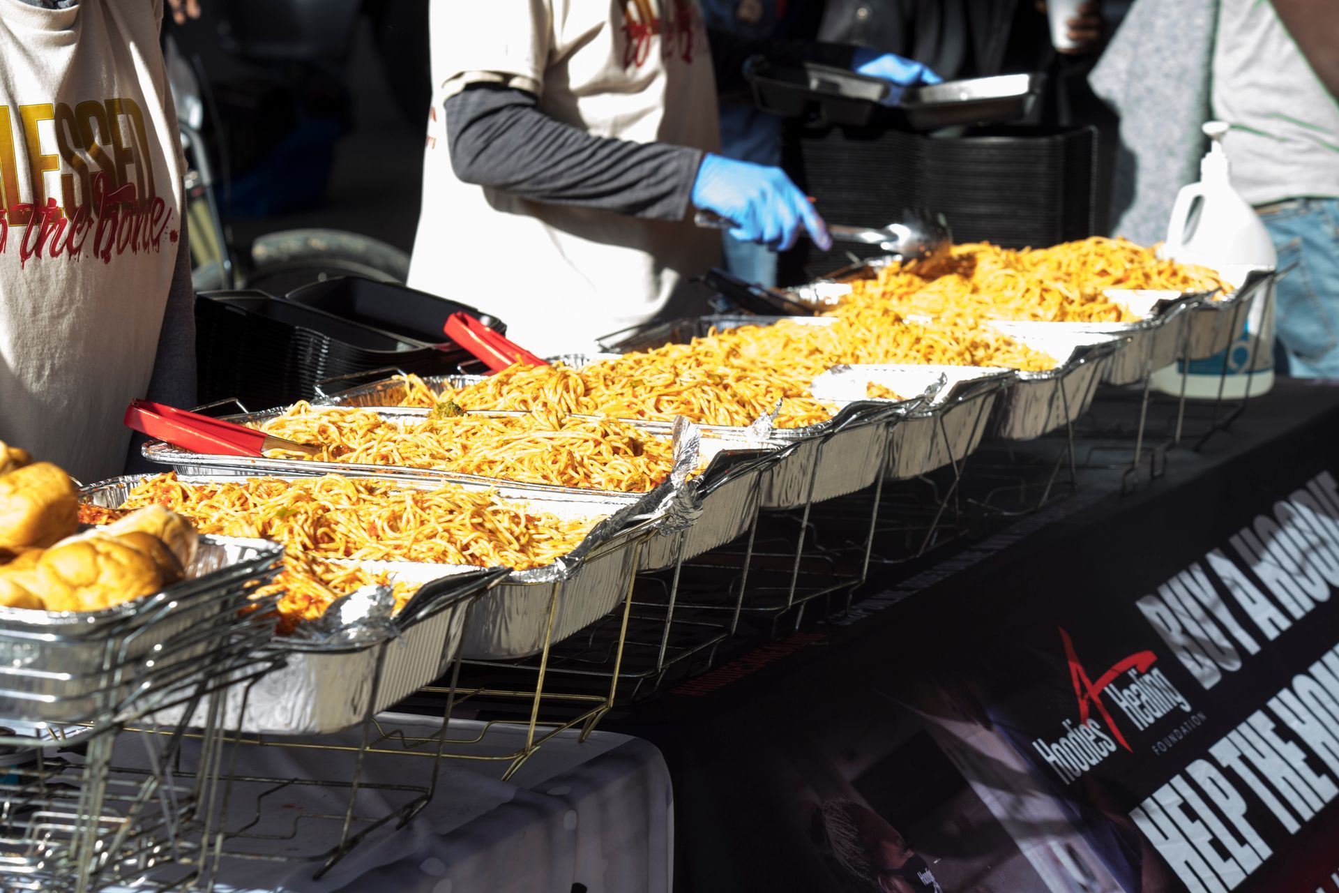 A person is serving food at a table with a sign that says 