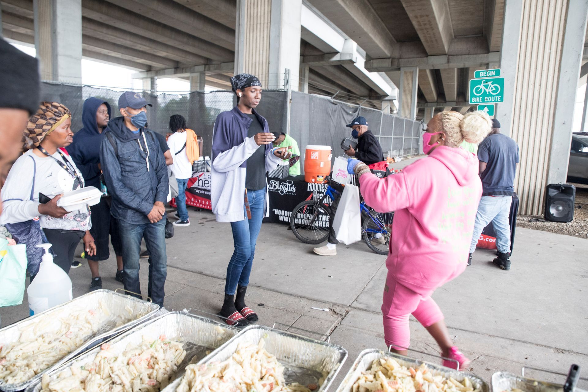 A woman in a pink hoodie is standing in front of a table of food.