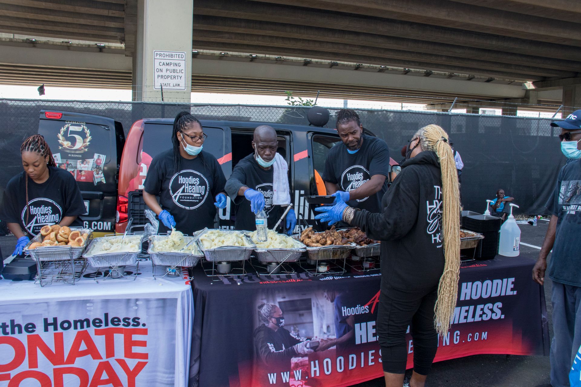 A group of people are standing around a table serving food.