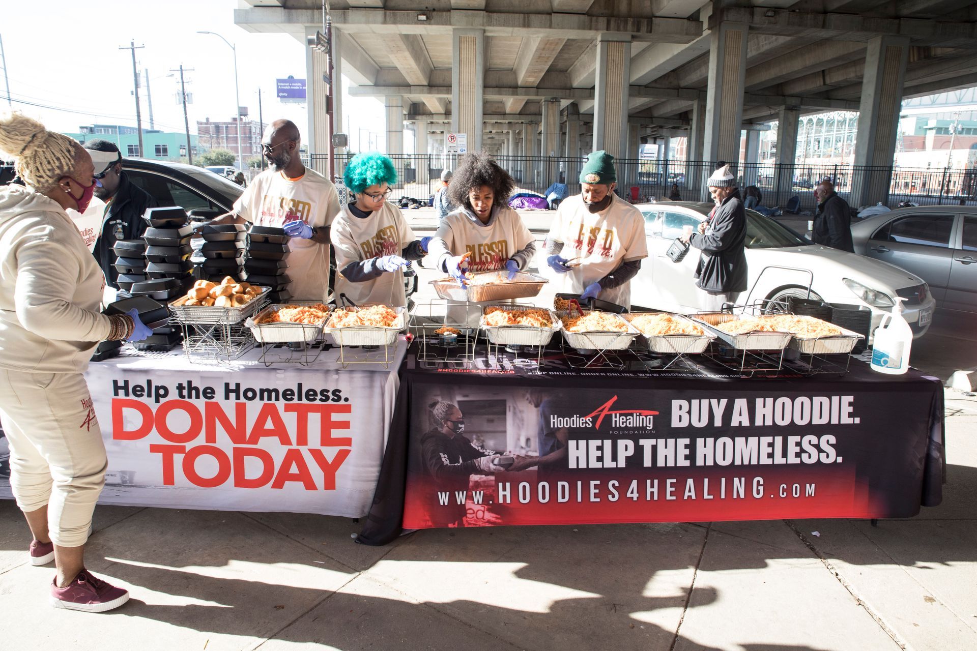 A group of people are standing around a table that says donate today.