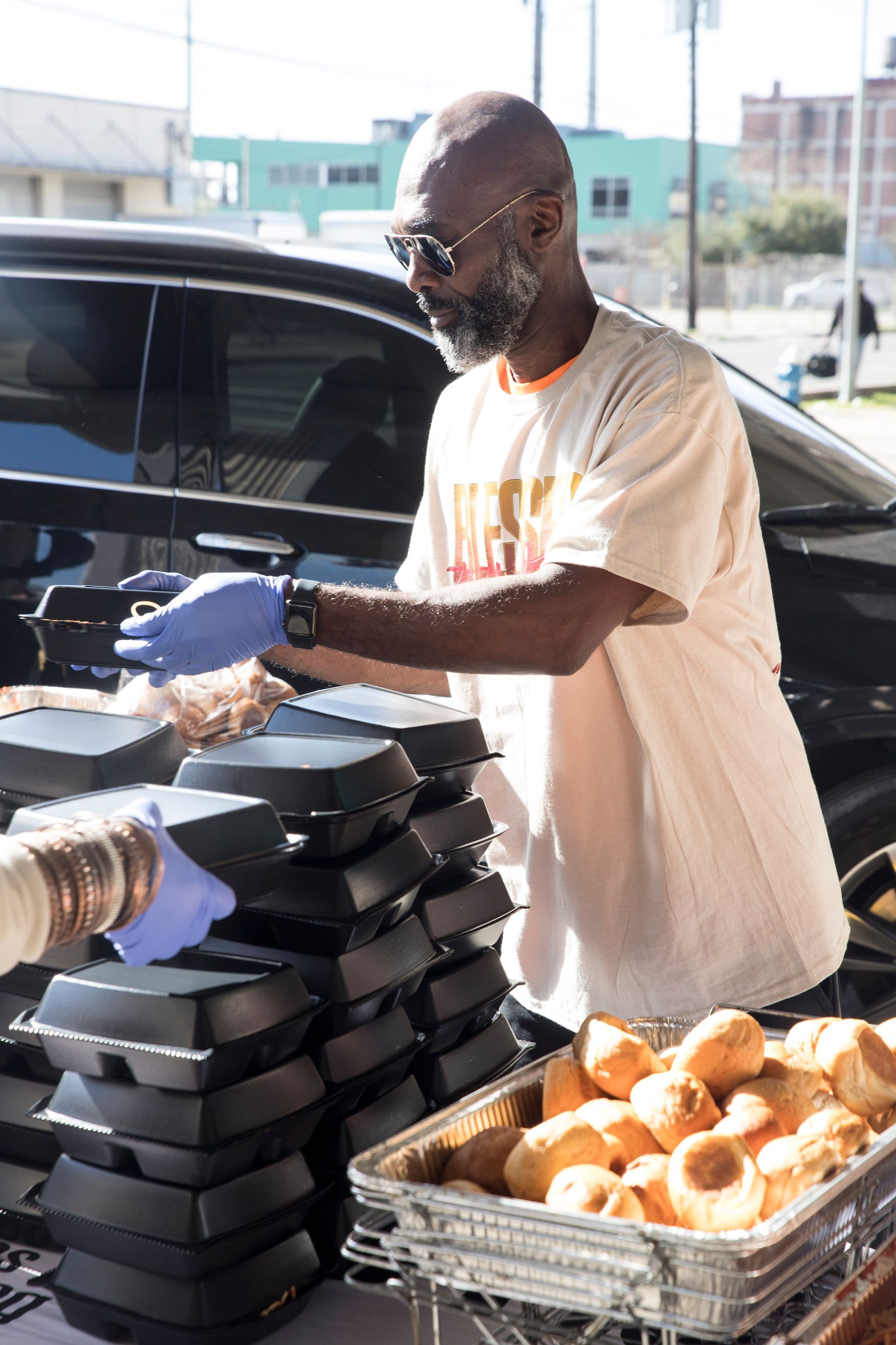 A man is serving food to a person in front of a car.