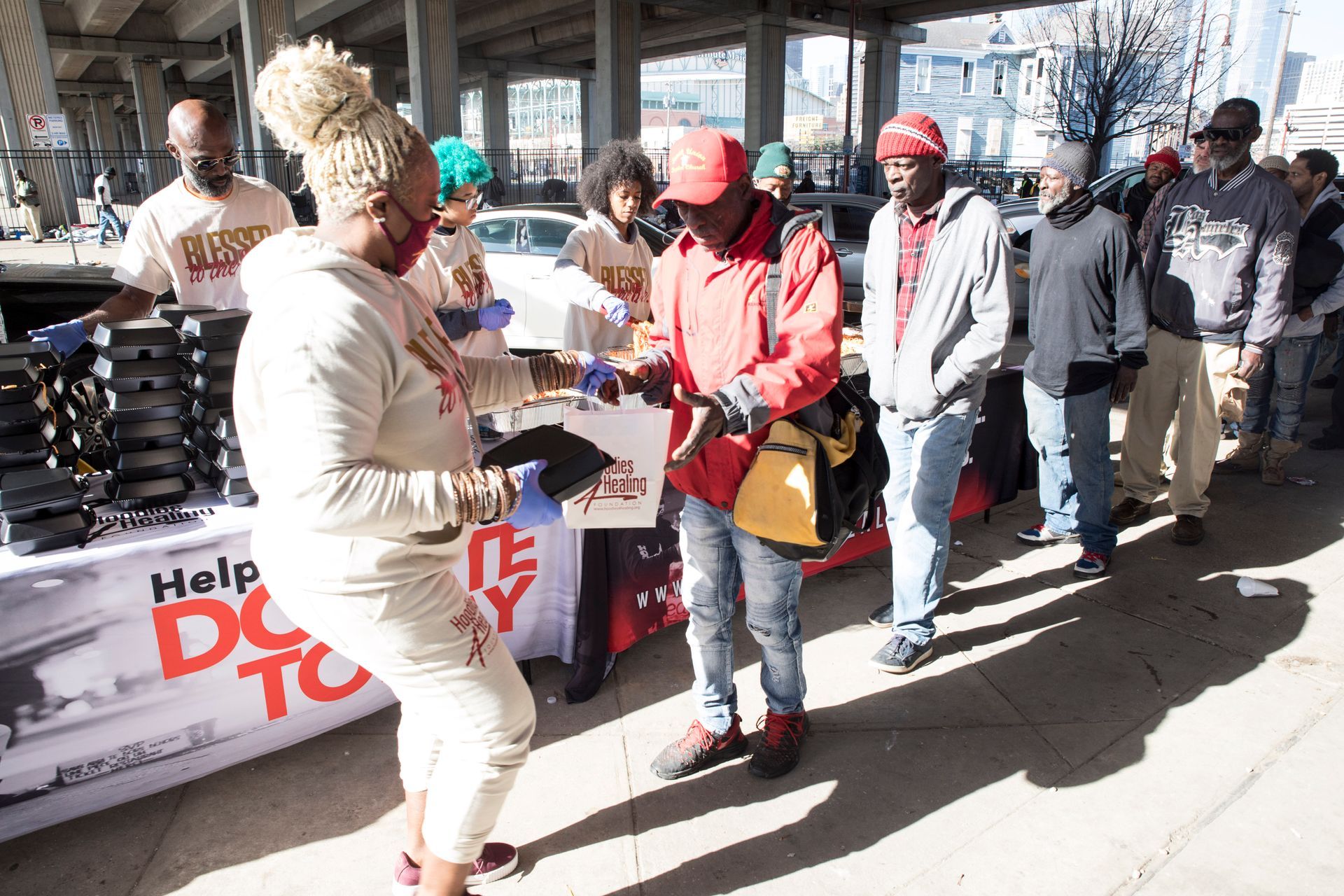 A group of people are standing around a table that says help do to