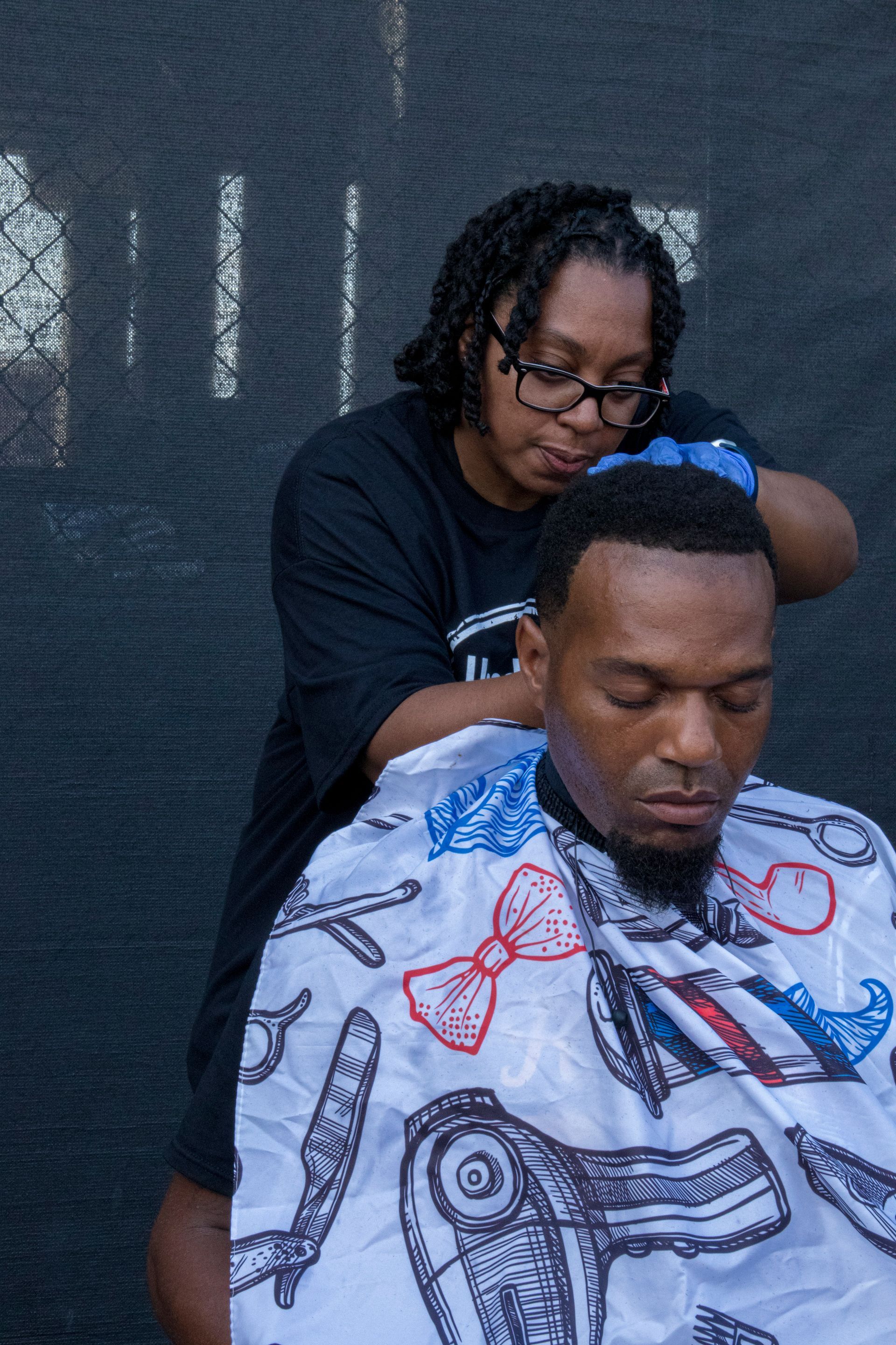A man is getting his hair cut by a woman.