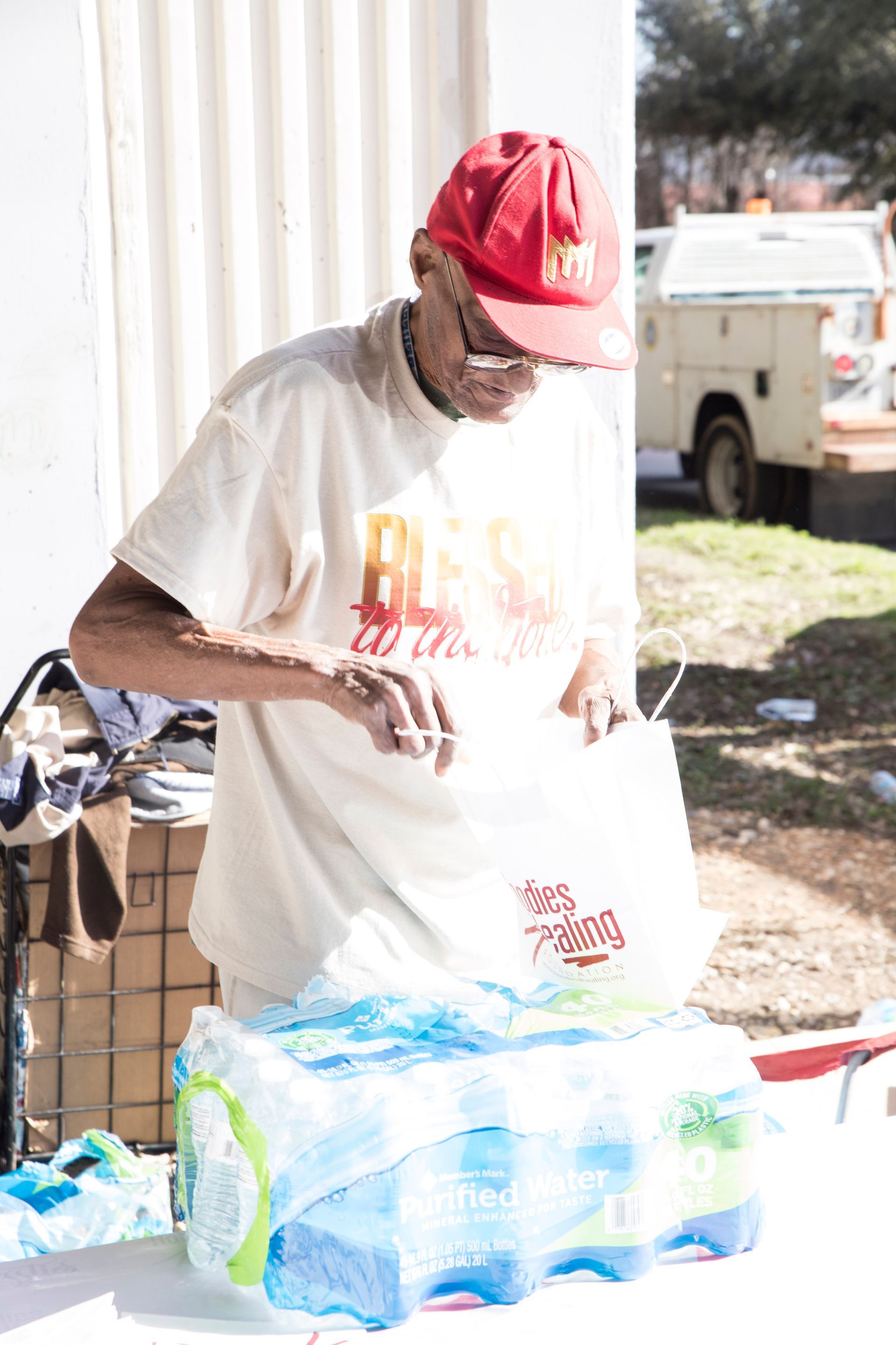 A man wearing a red hat is standing next to a table filled with water bottles.
