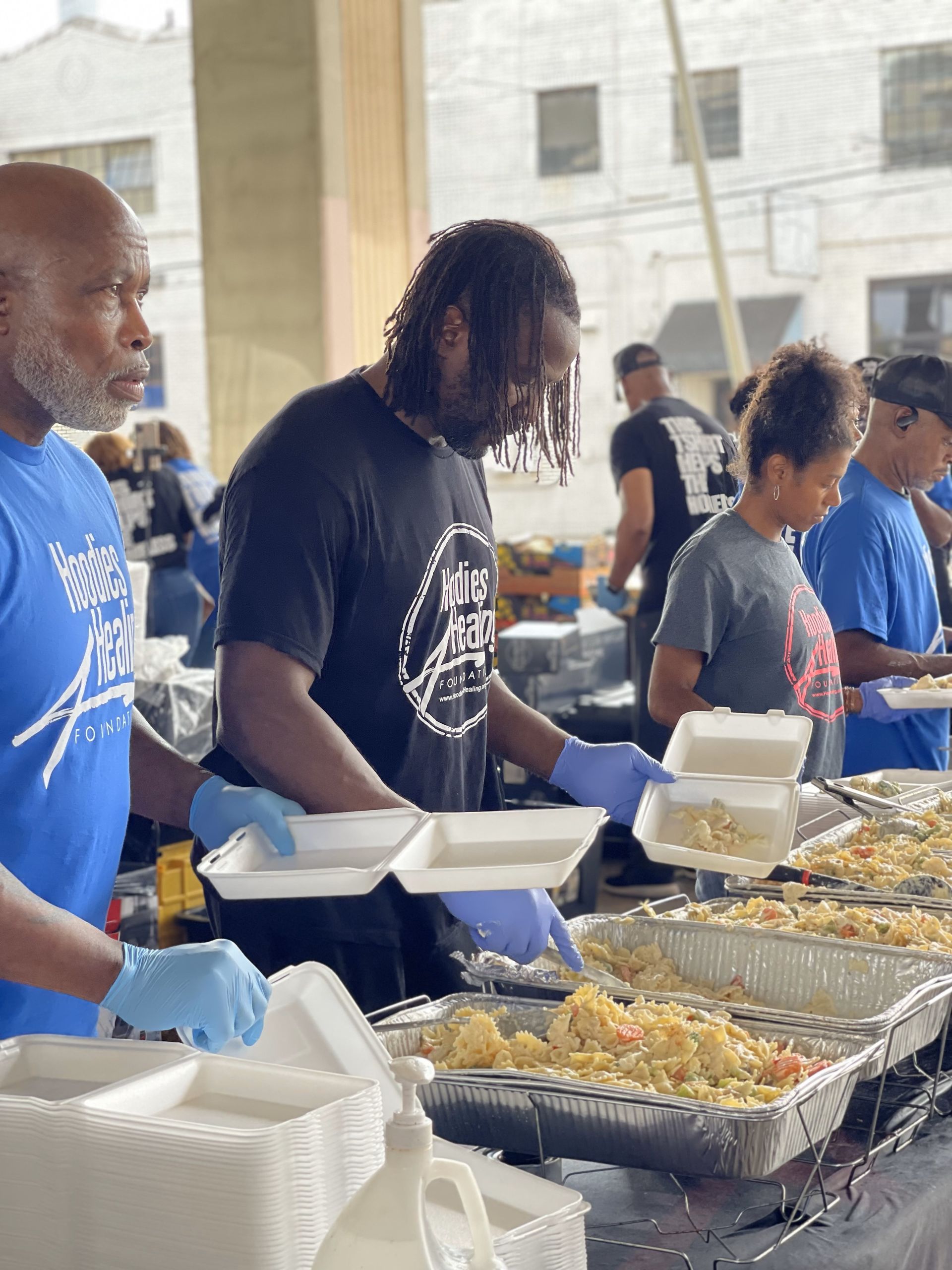 A group of people are standing around a table serving food.