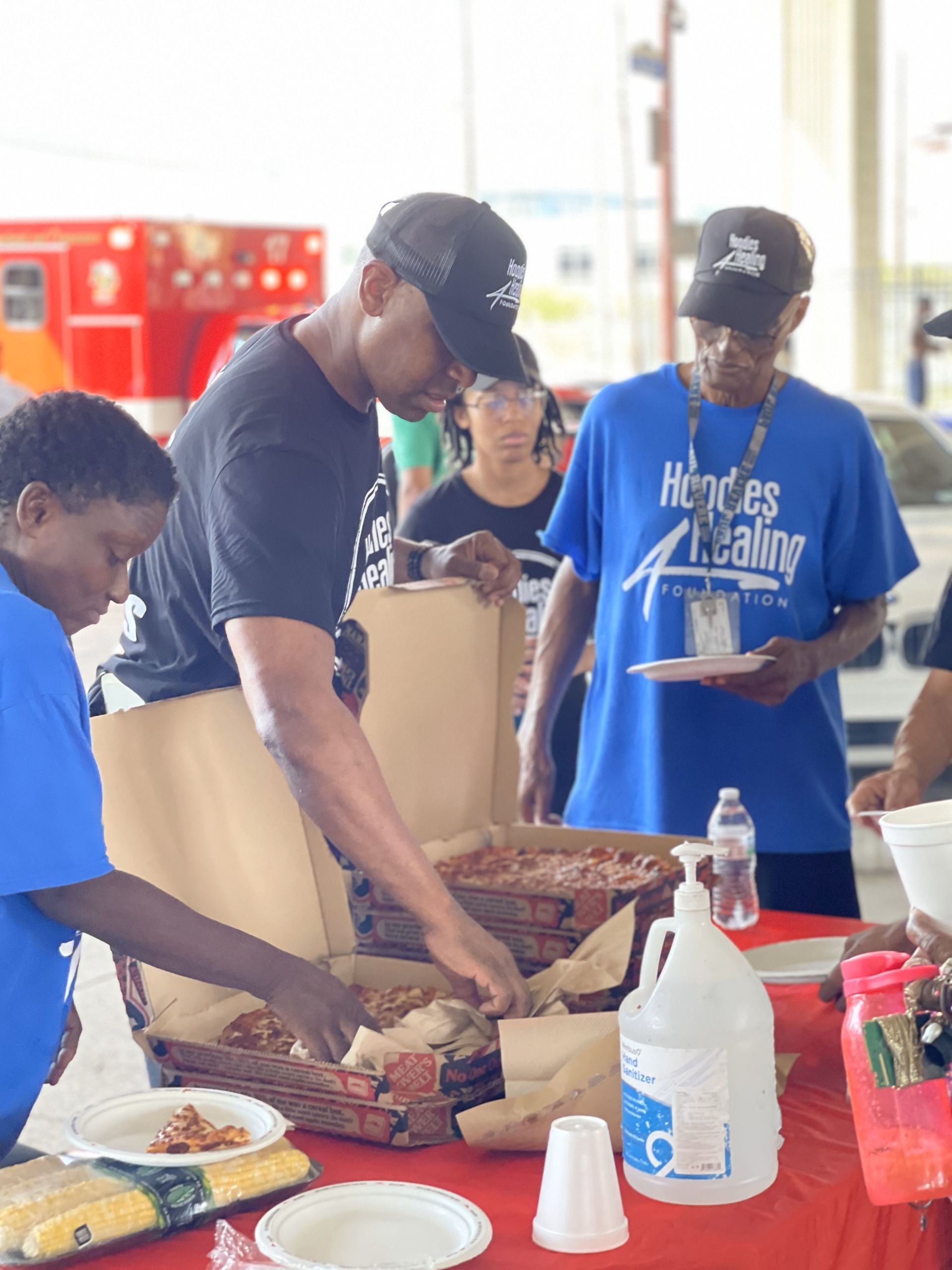 A group of people are standing around a table eating food.
