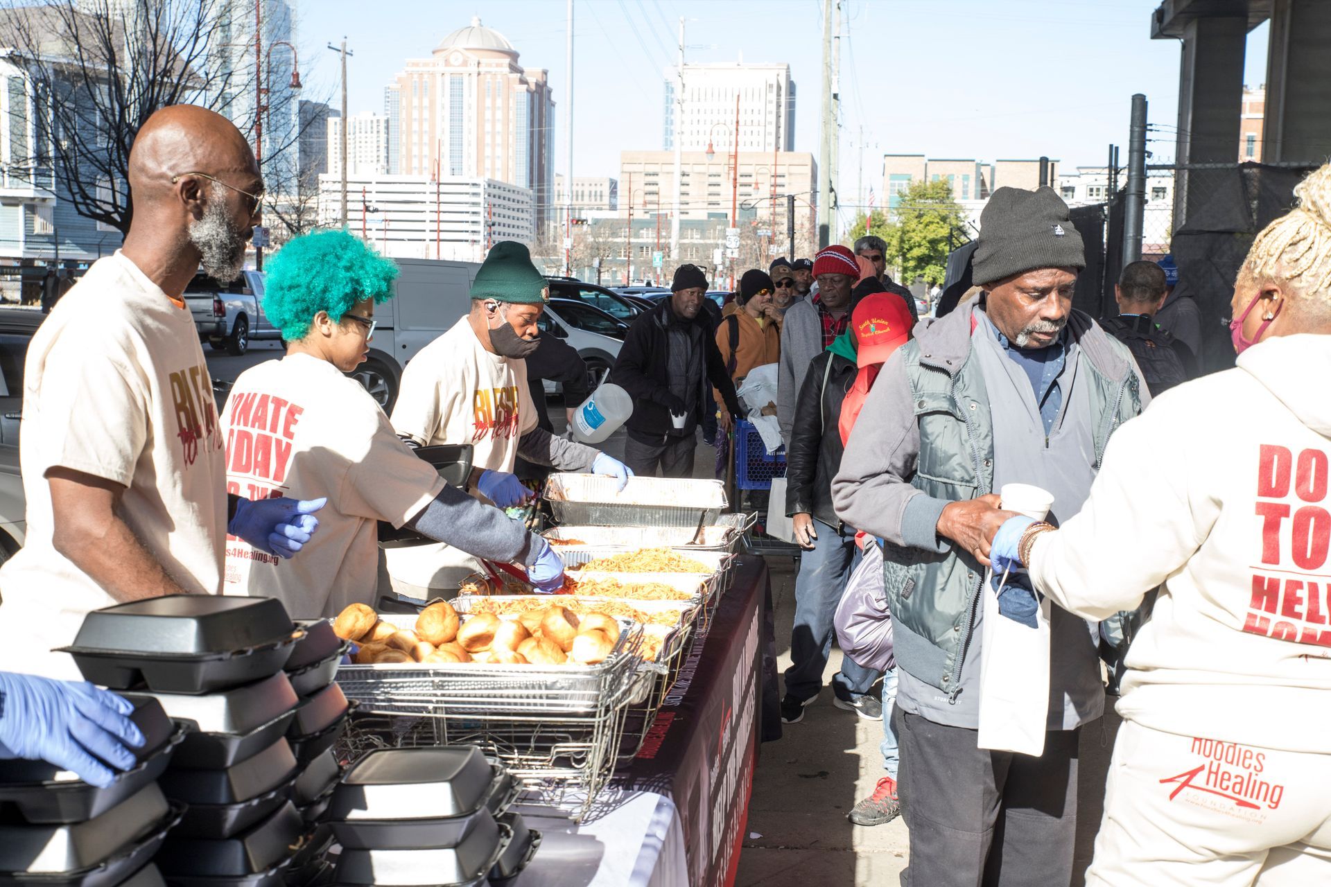 A group of people are standing around a table with a sign that says do to help