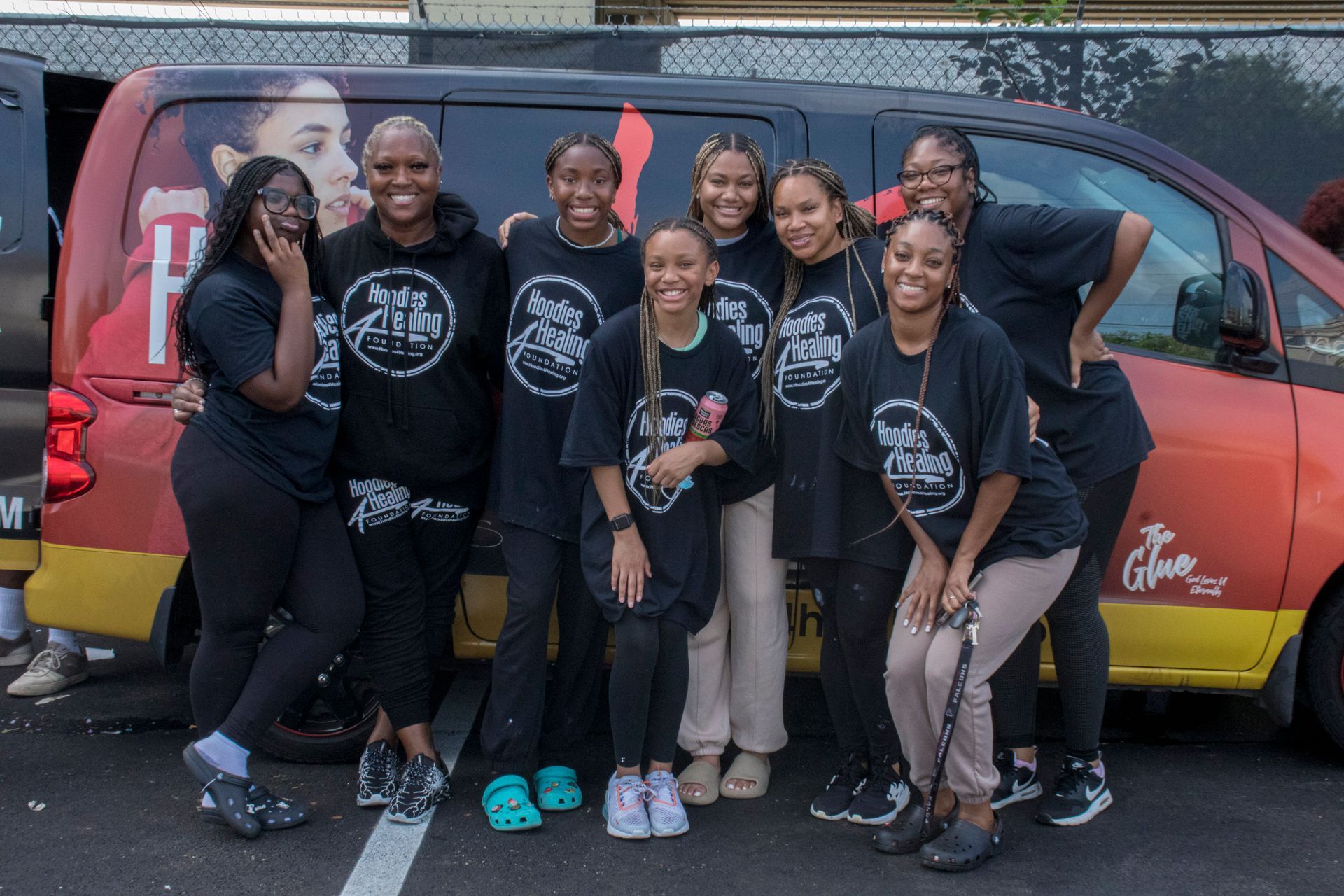 A group of women are posing for a picture in front of a van.