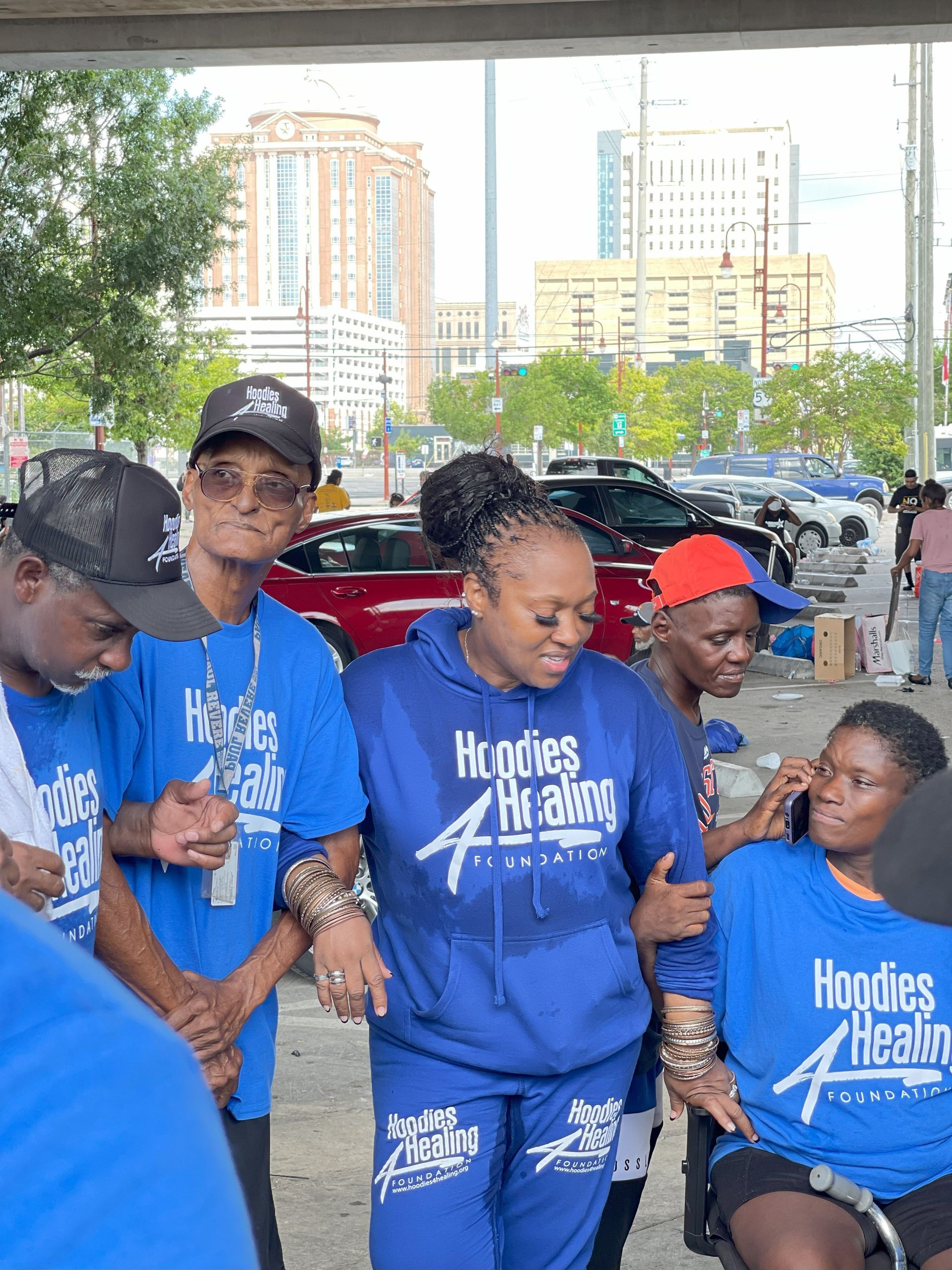 A group of people wearing blue shirts are standing next to each other in a parking lot.