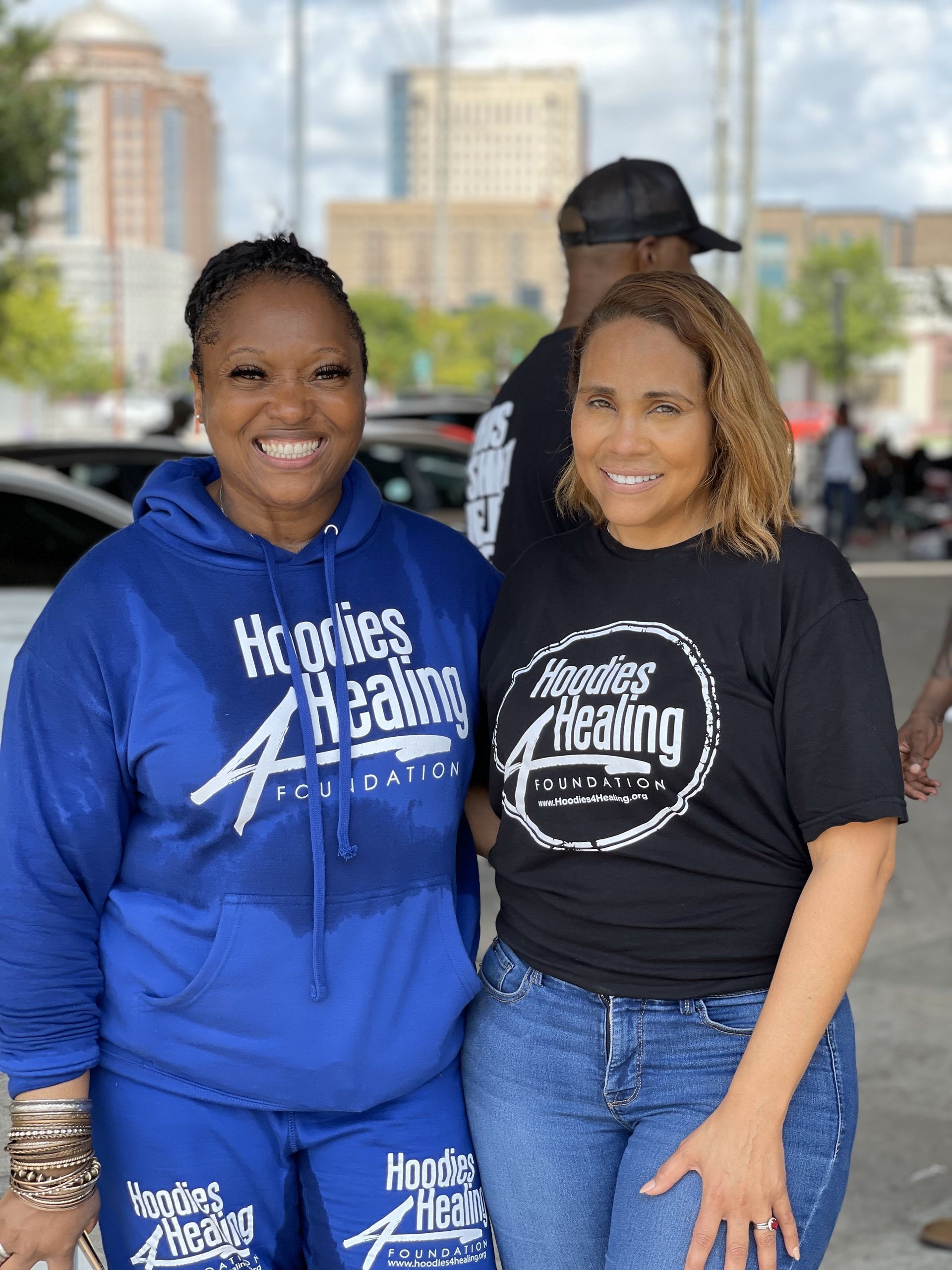 Two women wearing blue hoodies and black t-shirts are posing for a picture.