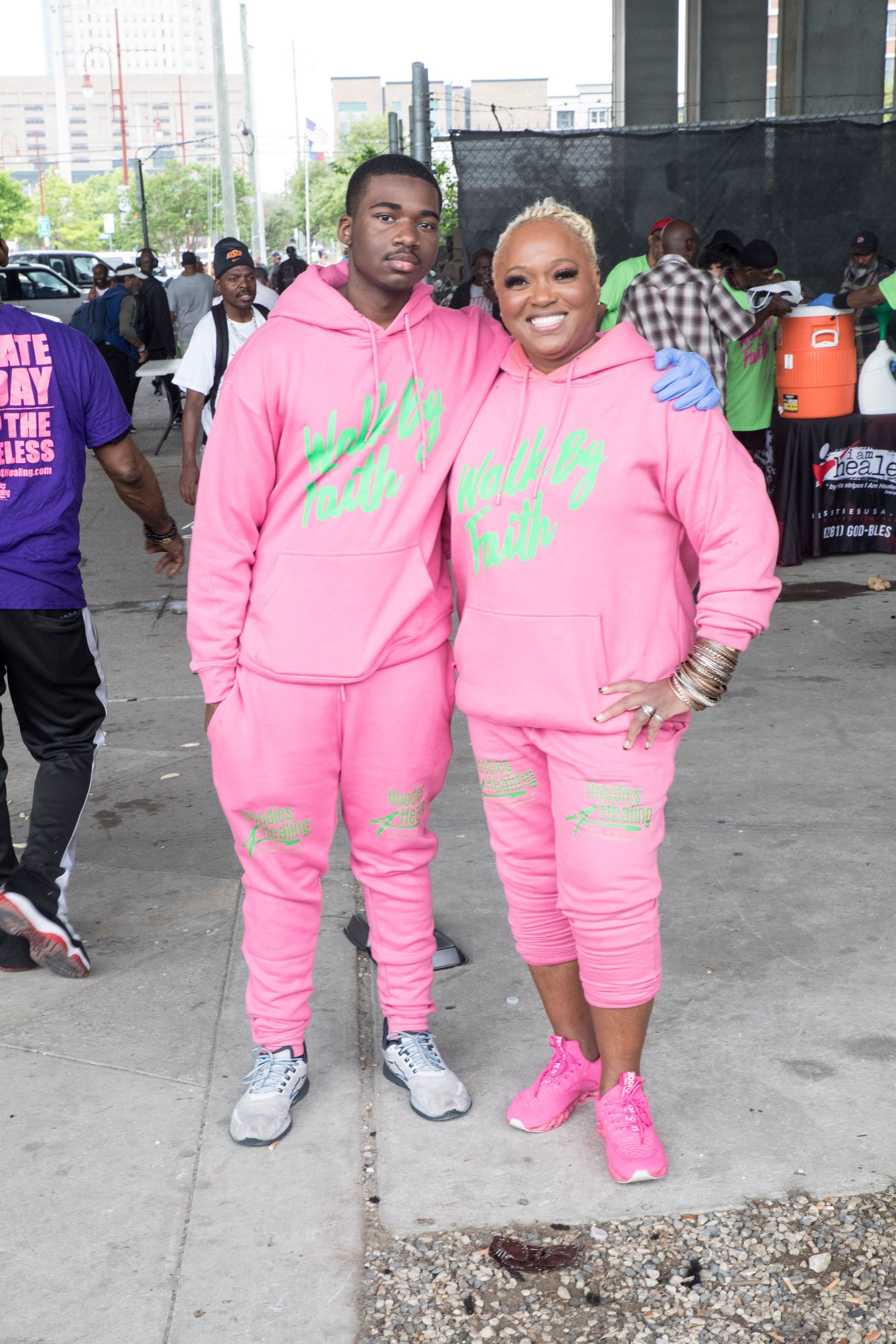 A man and a woman are standing next to each other wearing pink hoodies.