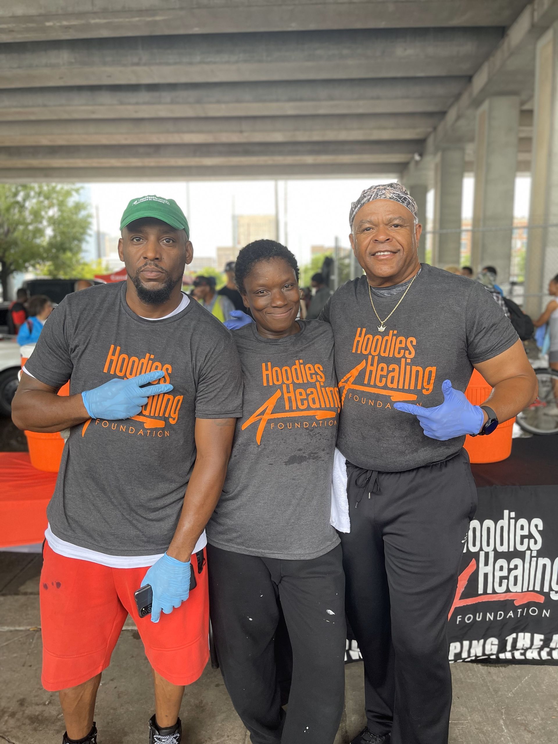 Three people are posing for a picture in front of a table that says bodies healing