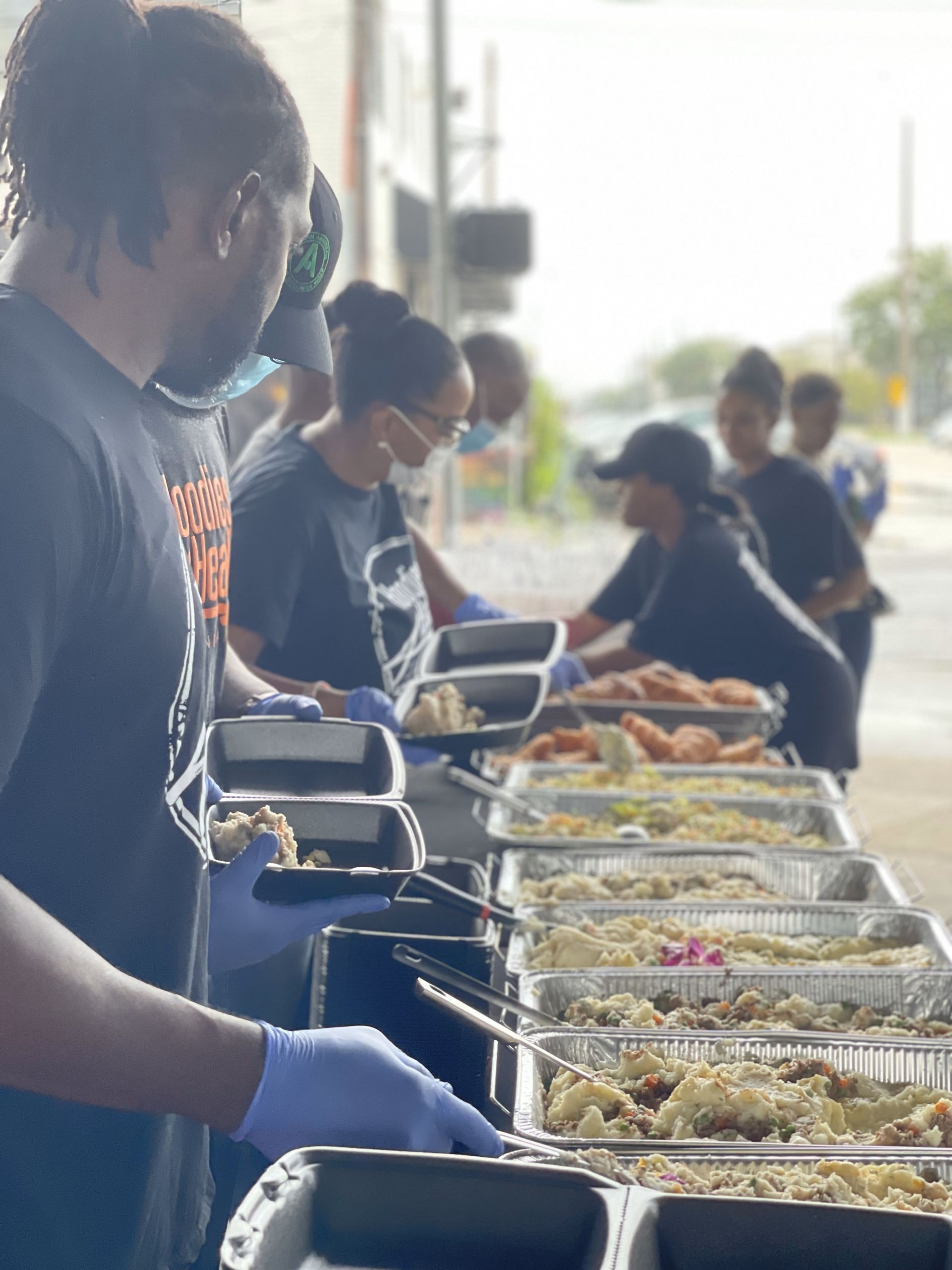 A group of people are preparing food at a buffet table.