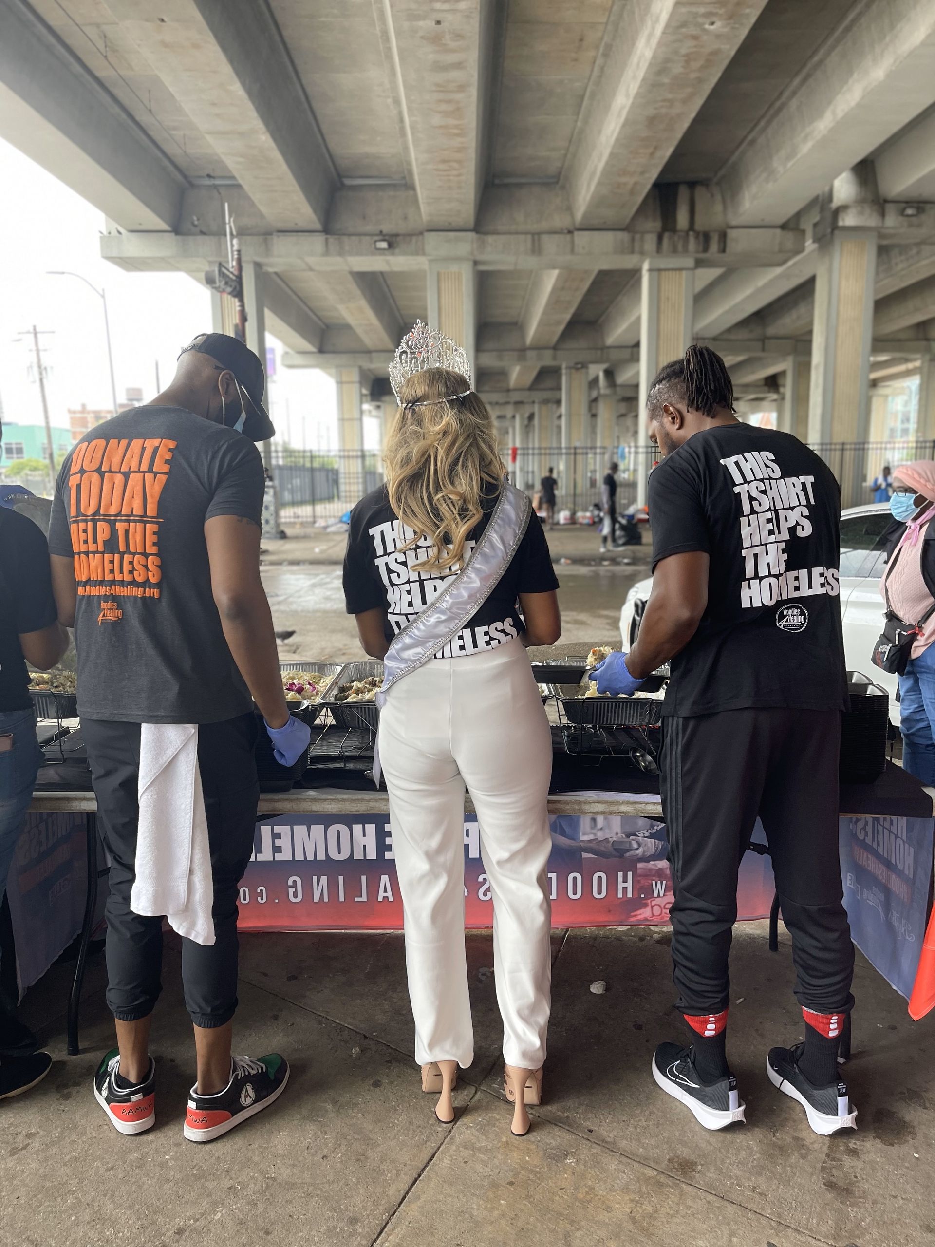 A group of people are standing around a table under a bridge.