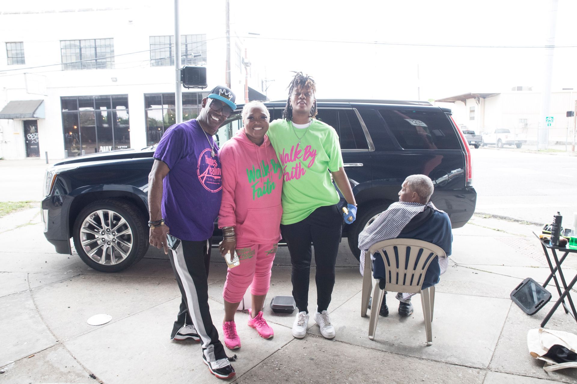 A group of people are posing for a picture in front of a car.