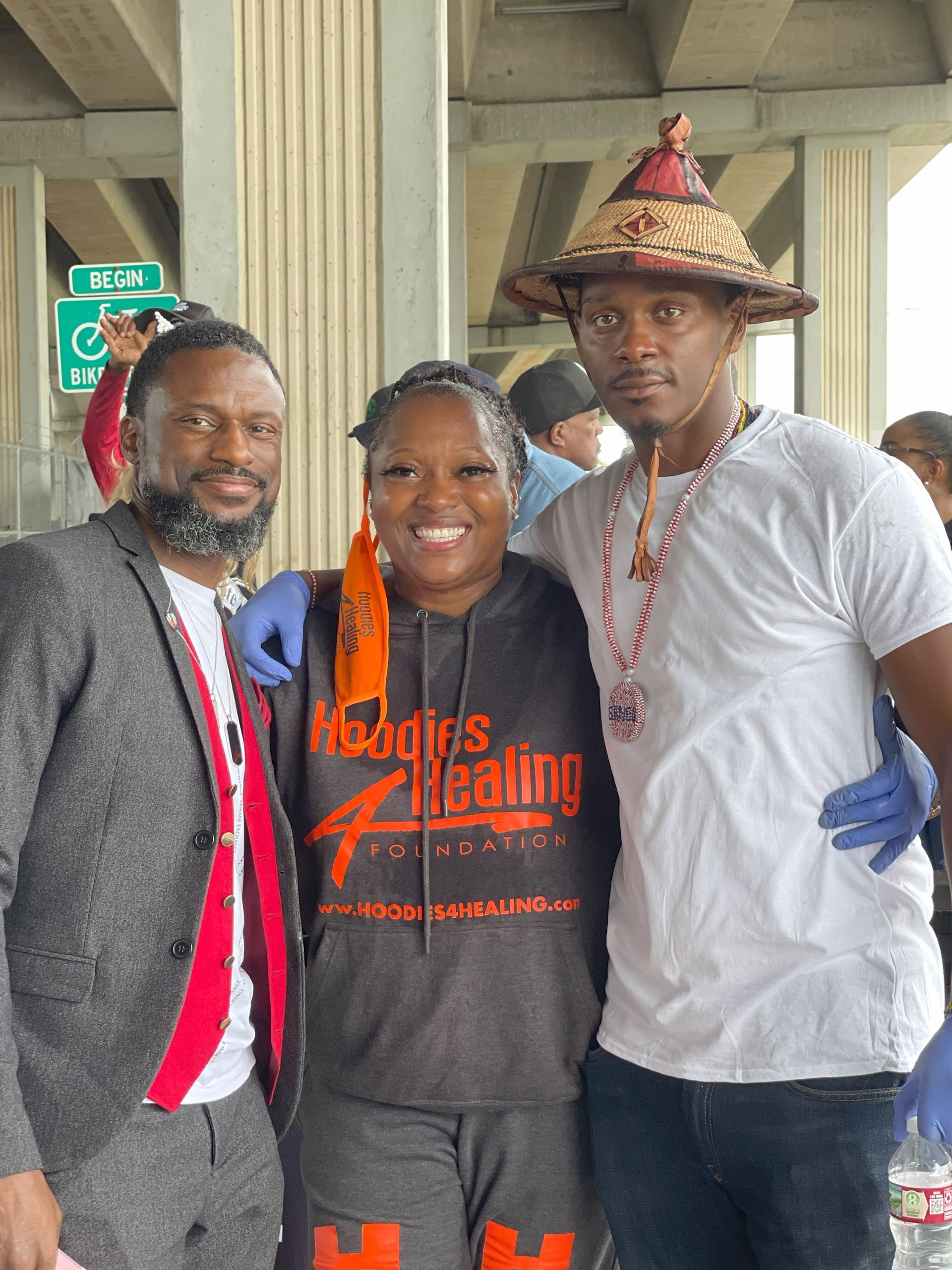 Two men and a woman are posing for a picture under a bridge.