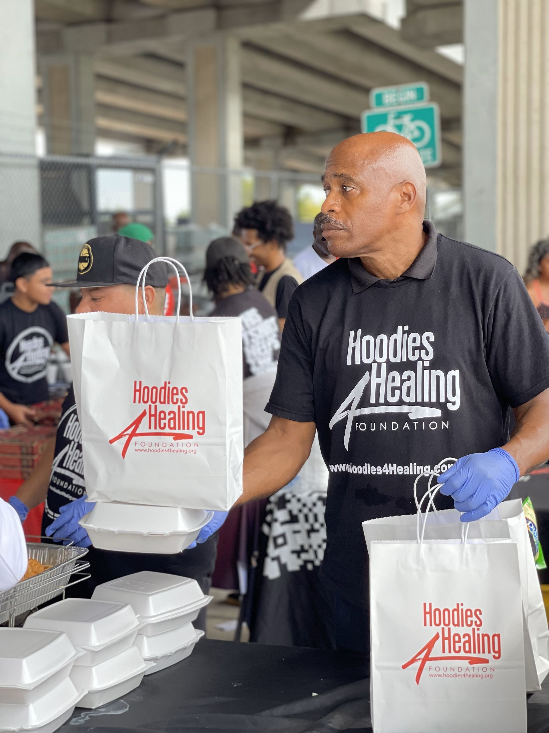 A man wearing a hoodies healing shirt is holding a bag of food.