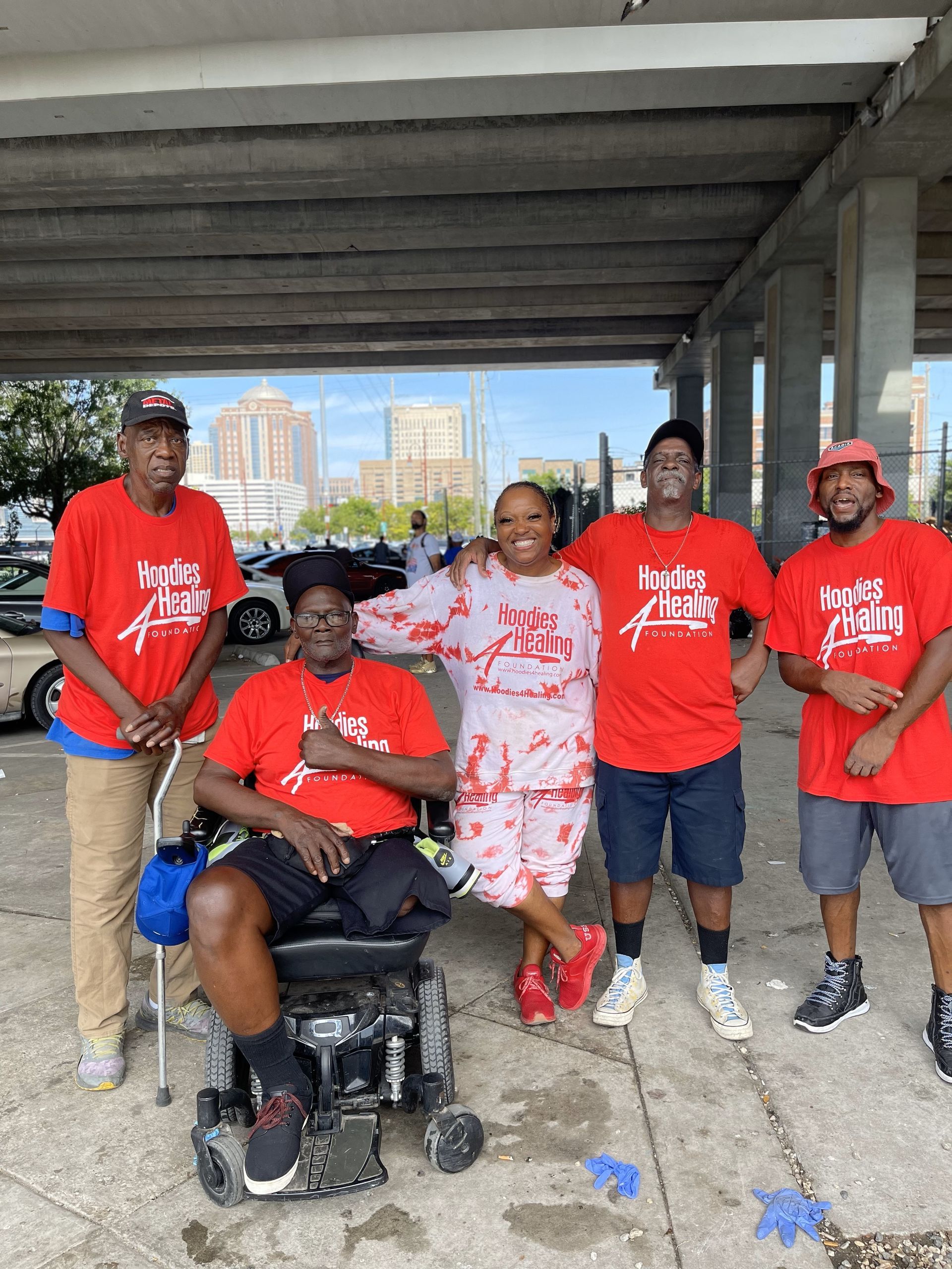 A group of people wearing red shirts are posing for a picture with a man in a wheelchair.