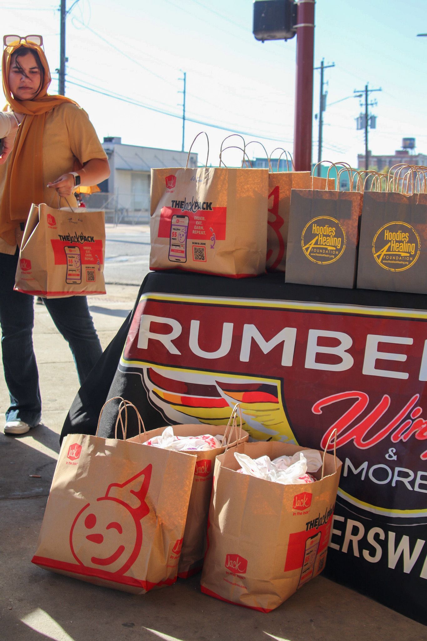 A woman is standing in front of a table with rumbel bags on it