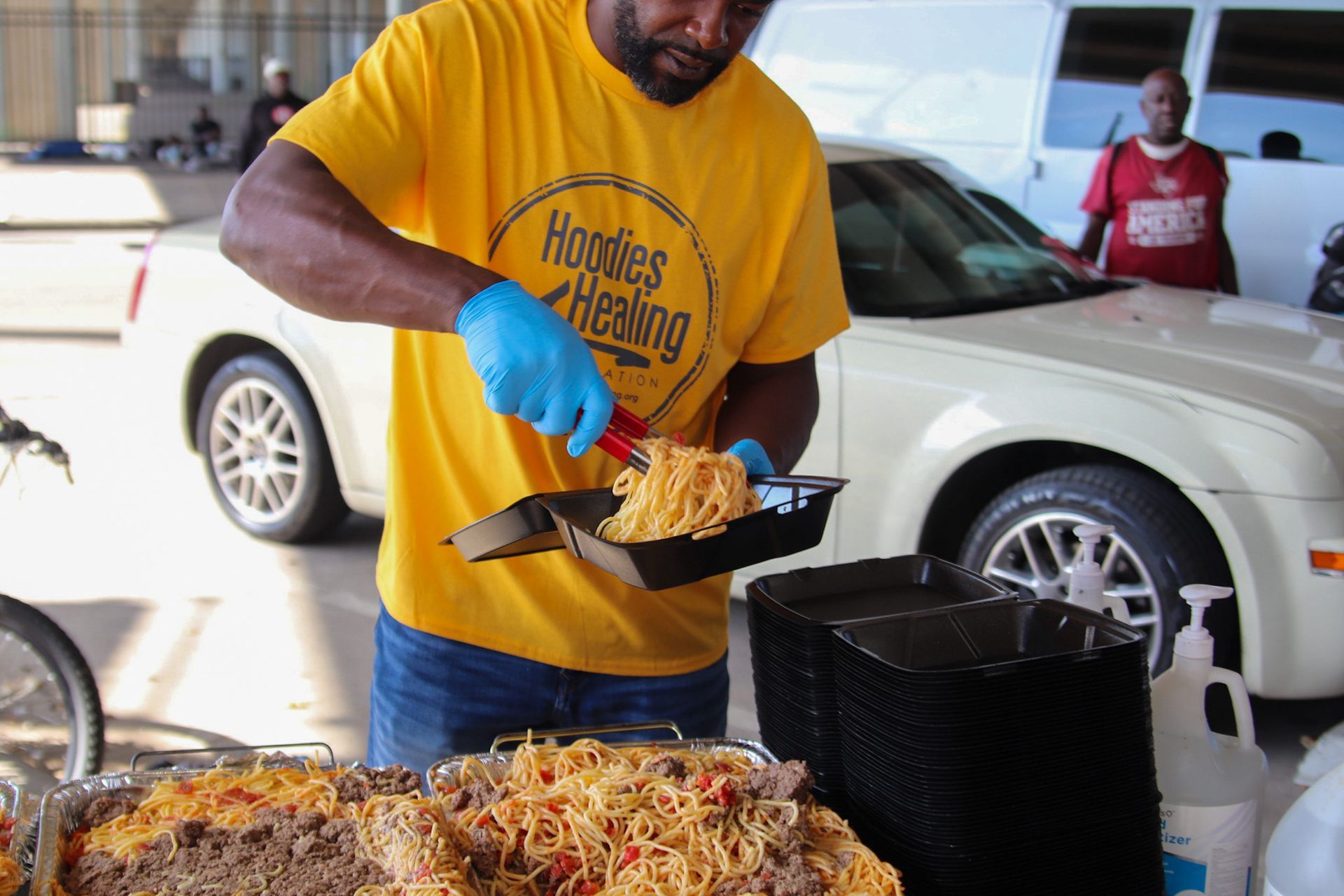 A man wearing a yellow shirt that says hooters racing is serving food