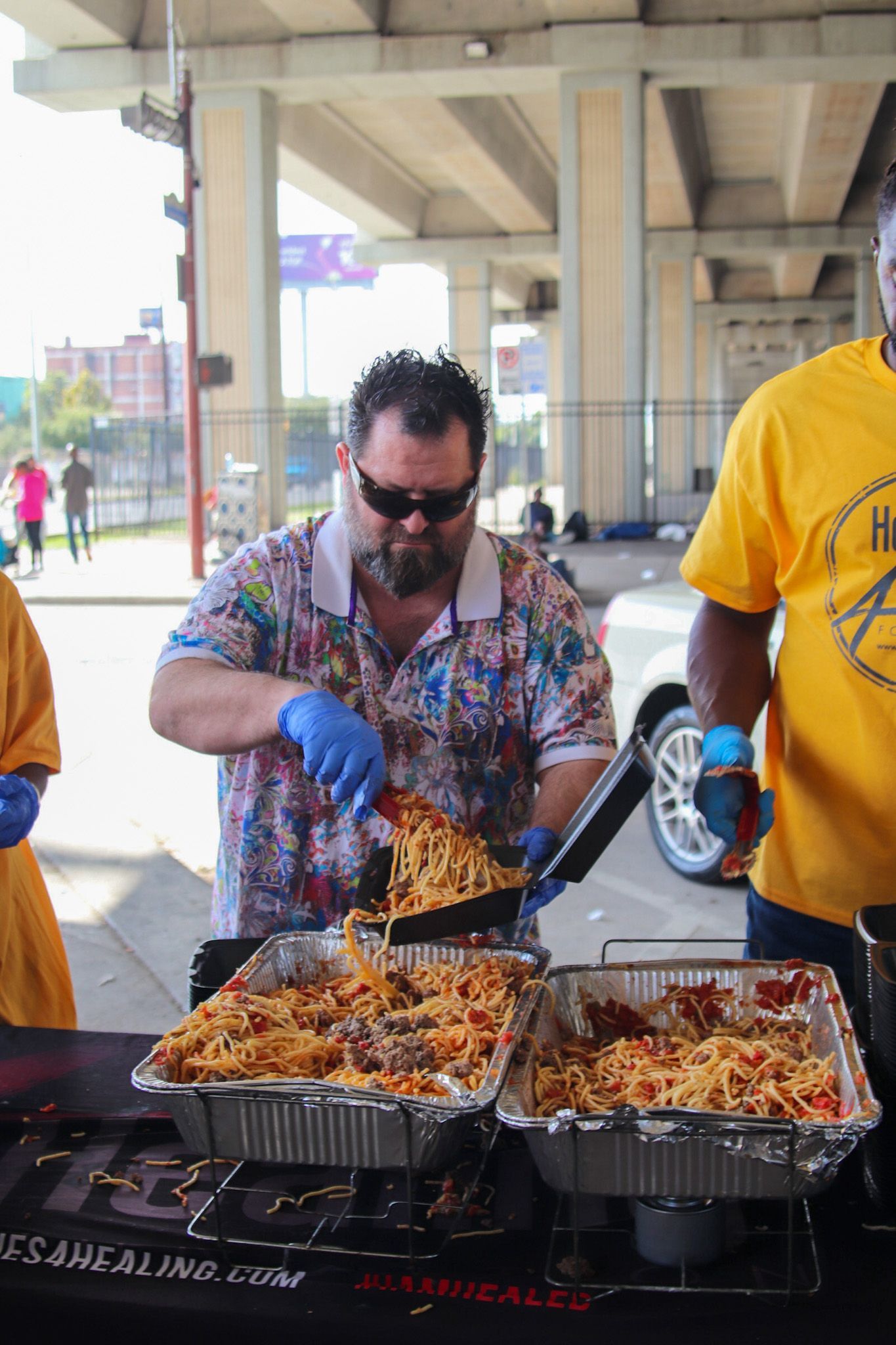 A man in a yellow shirt is cooking food on a table.