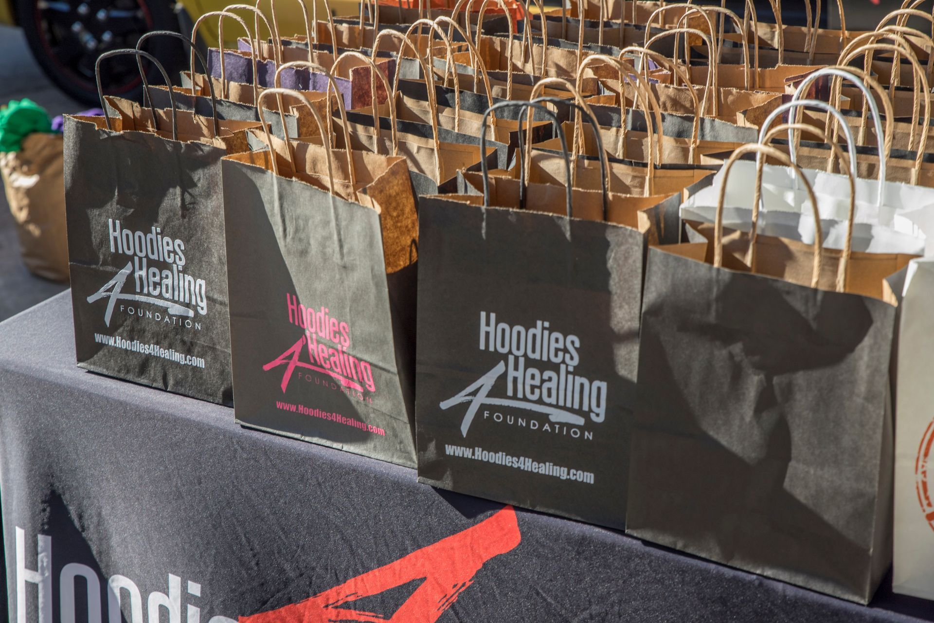 A table topped with bags that say hoodies healing