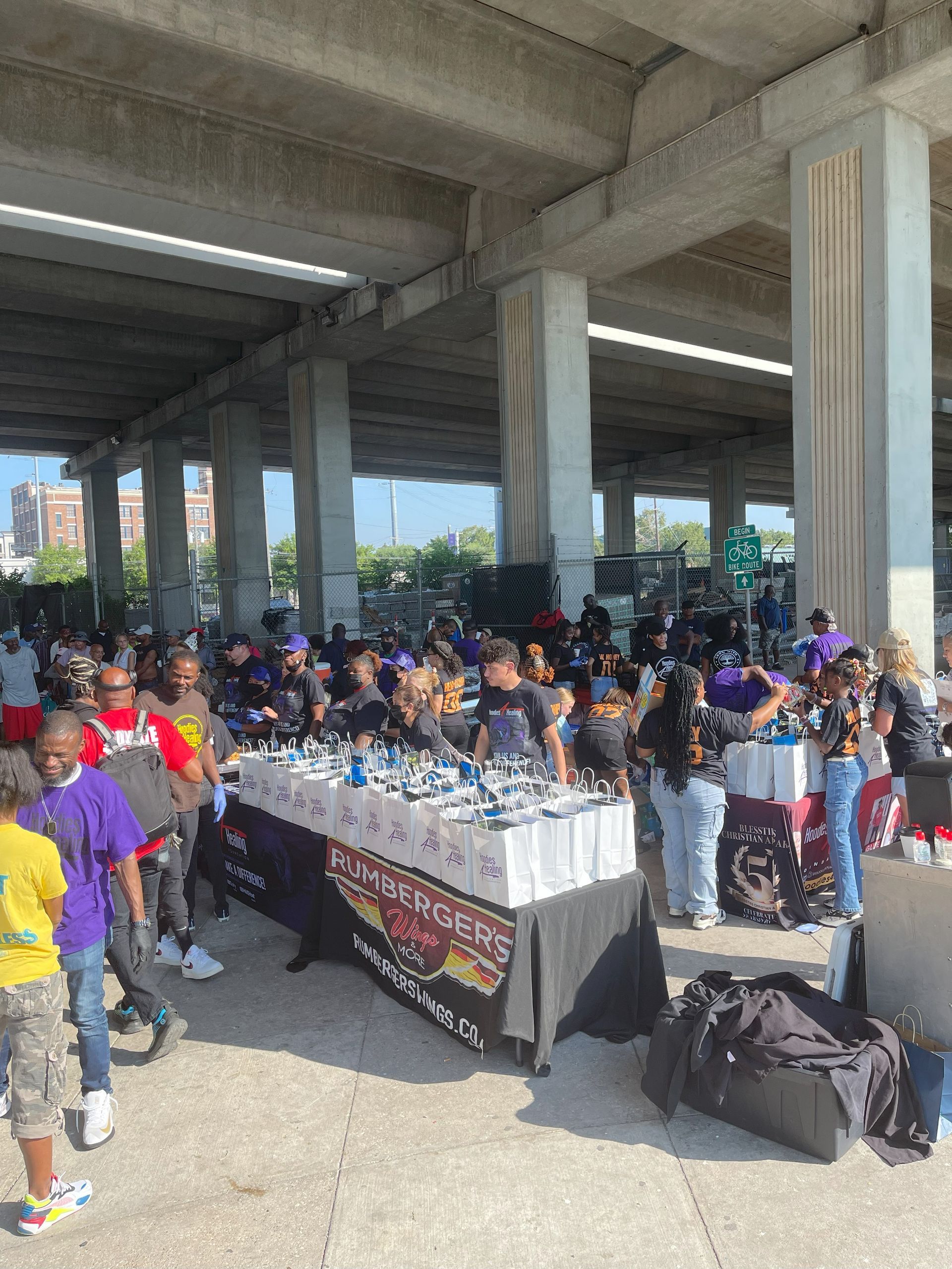 A group of people are standing around a table under a bridge.