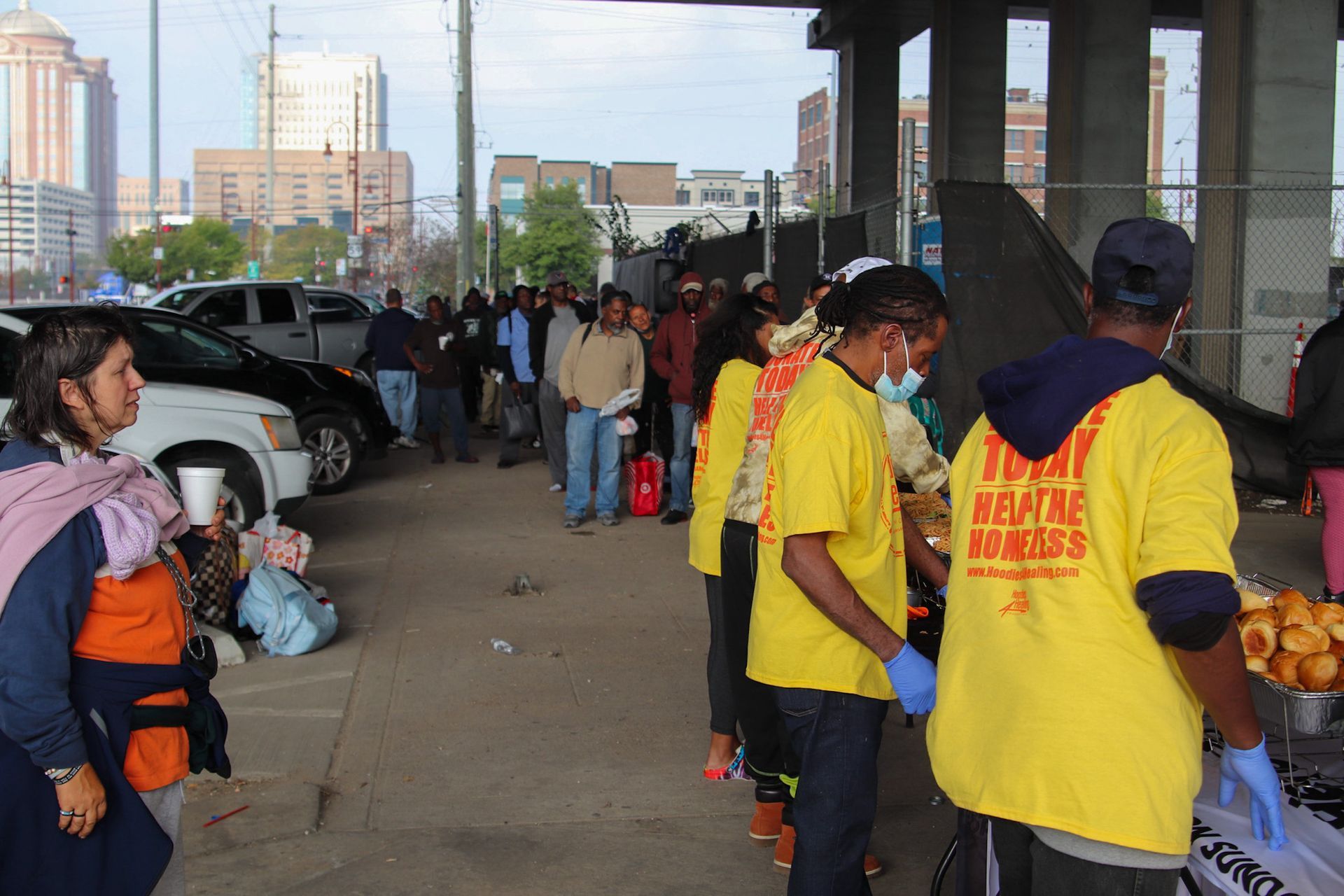 A group of people in yellow shirts are standing in a parking lot.