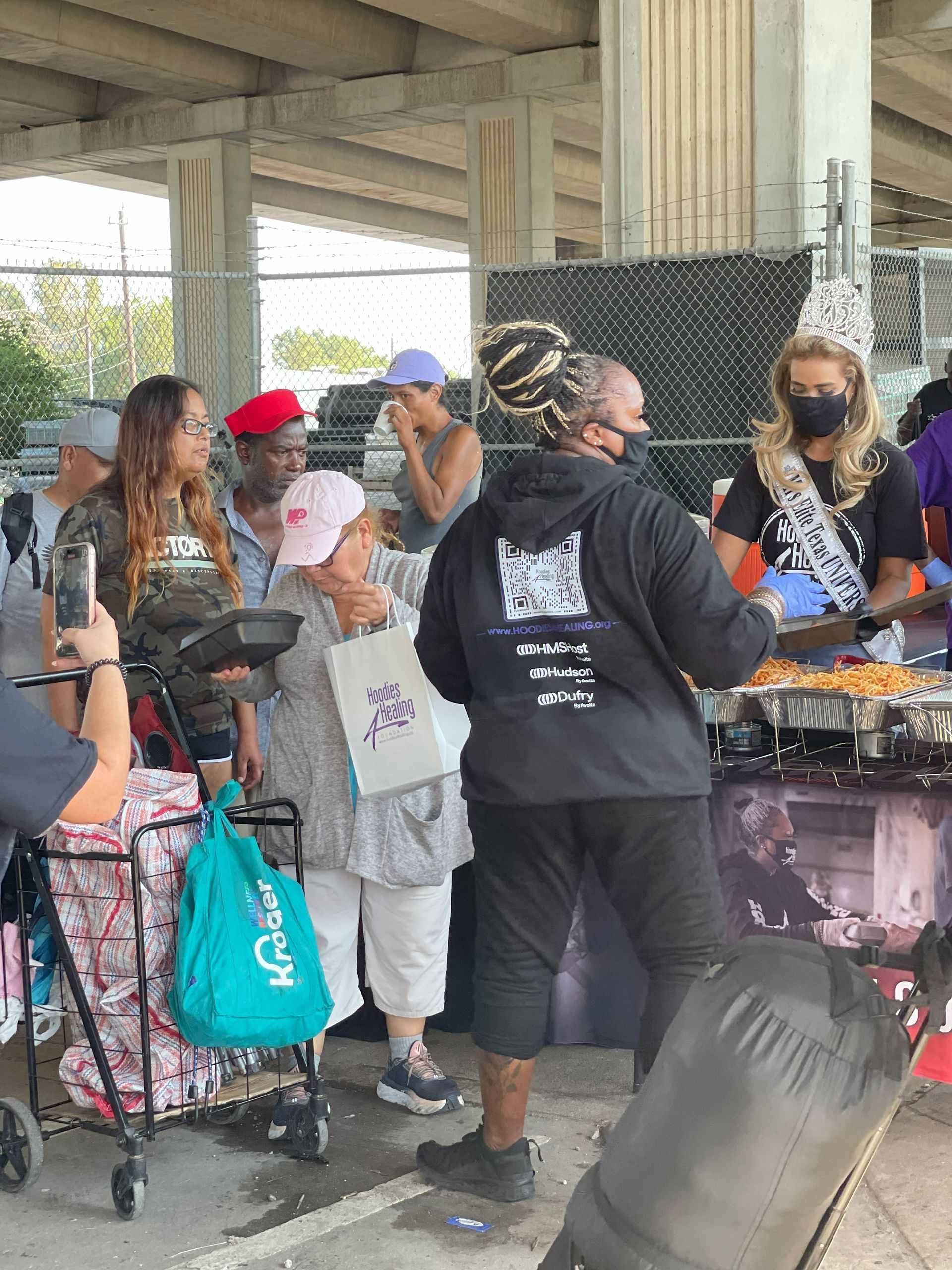 A group of people are standing around a table with food.