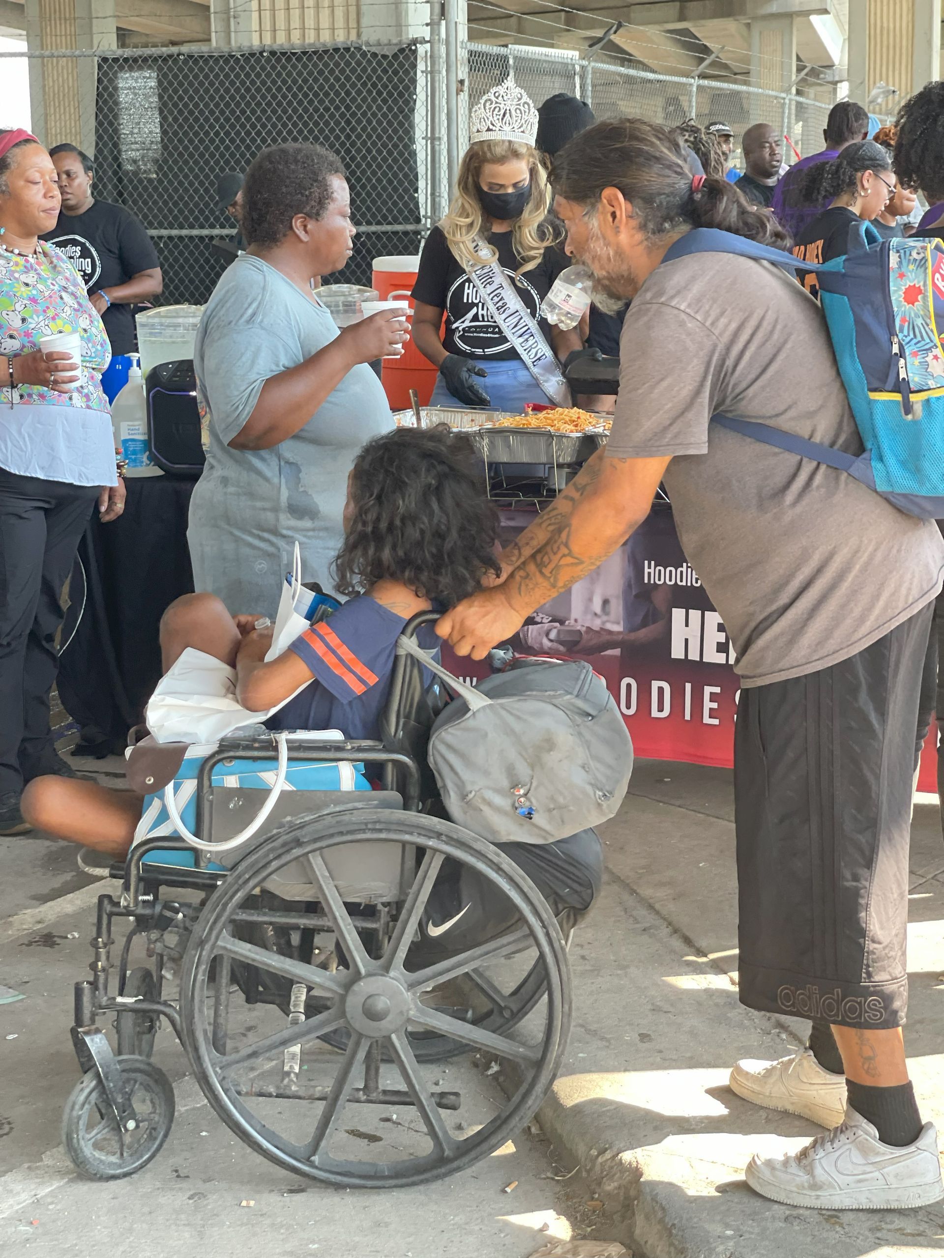 A group of people are standing around a child in a wheelchair.