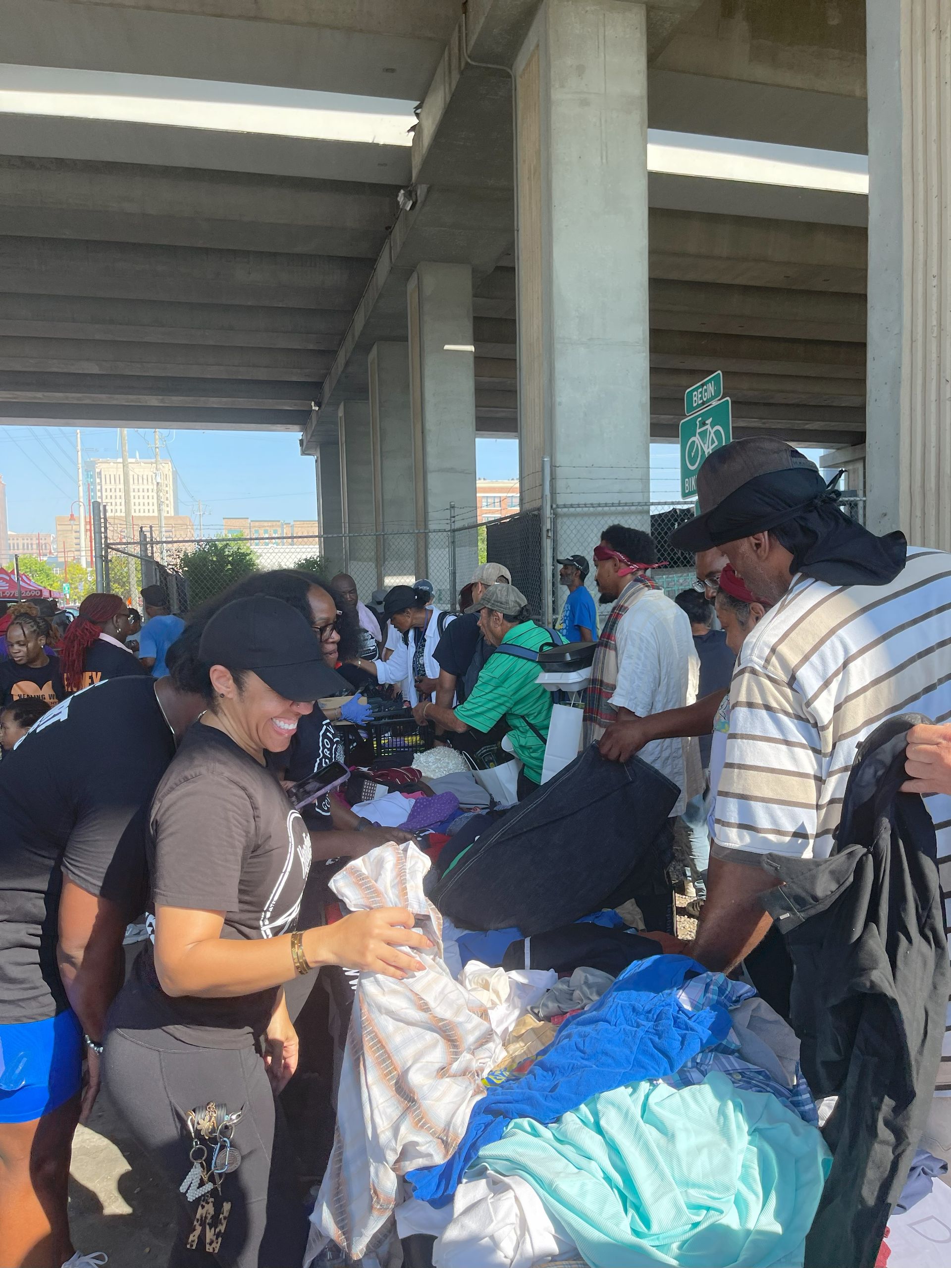 A group of people are standing around a pile of clothes.