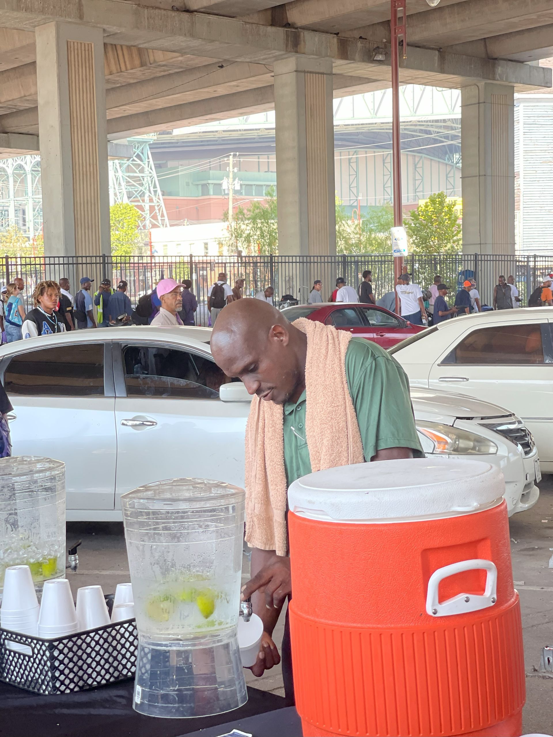 A man with a towel around his neck is standing next to an orange cooler
