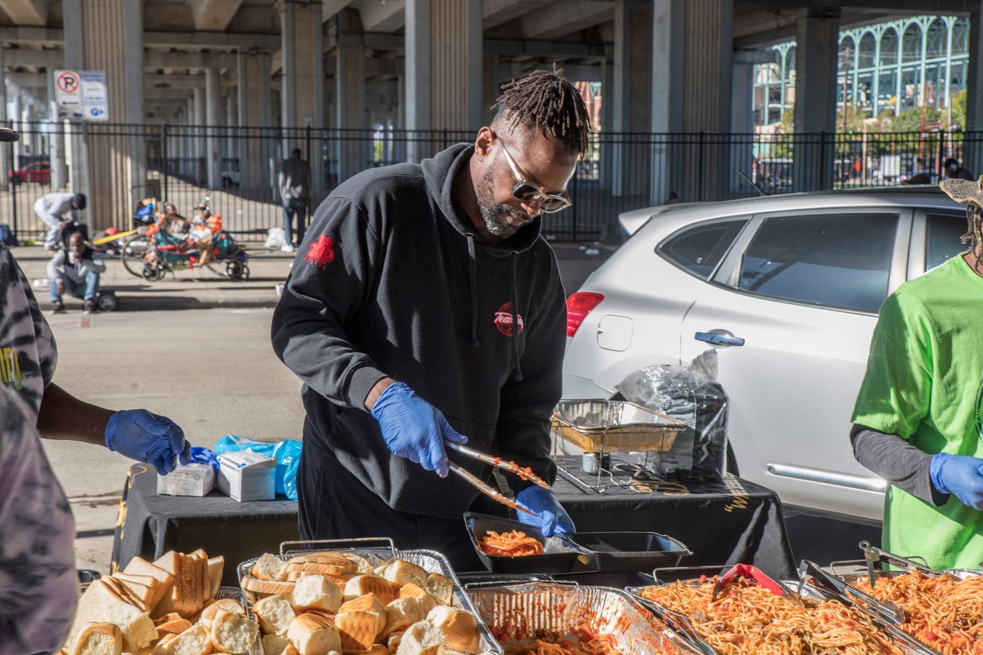 A man is cooking food on a grill in a parking lot.