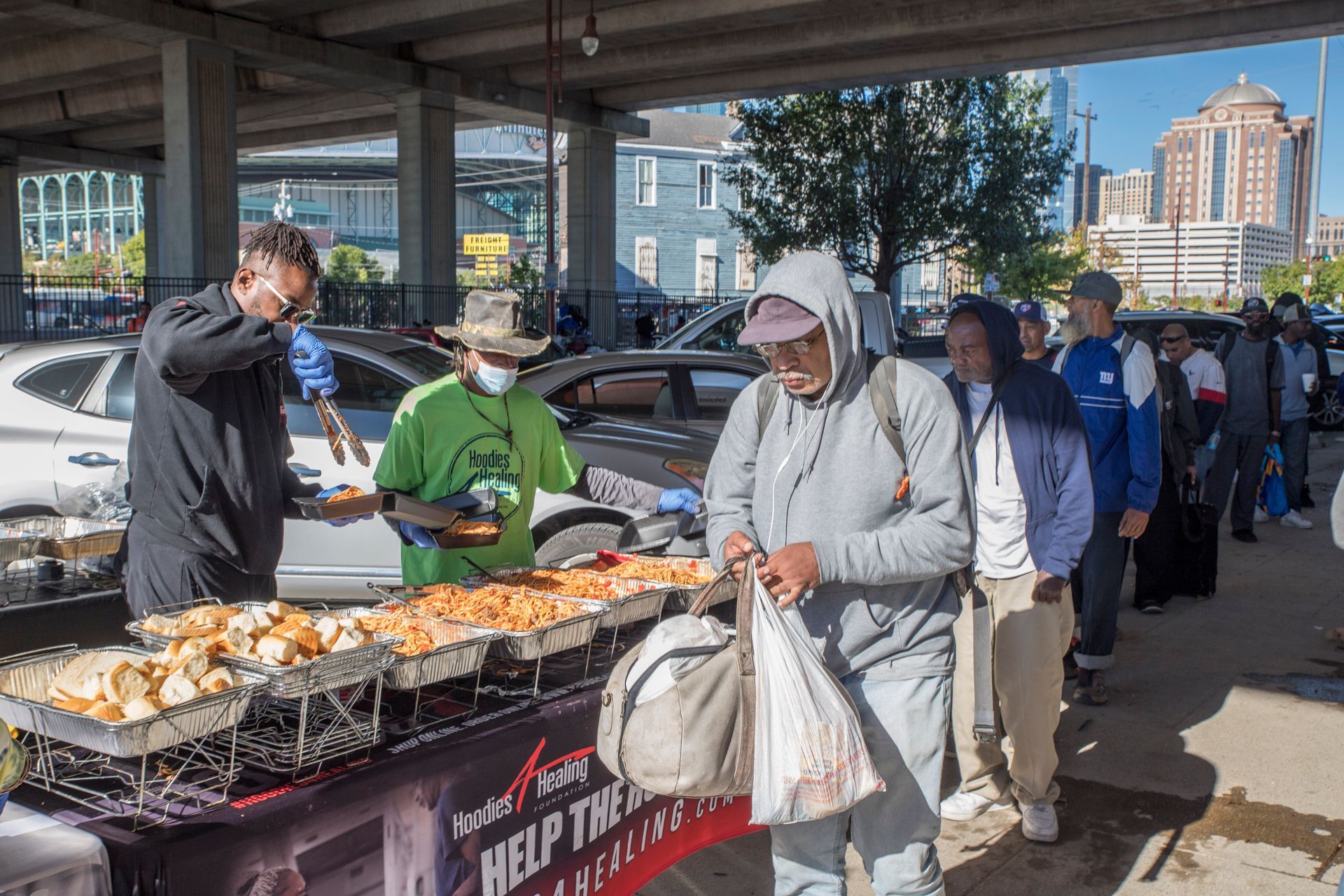 A group of people are standing around a table eating food.
