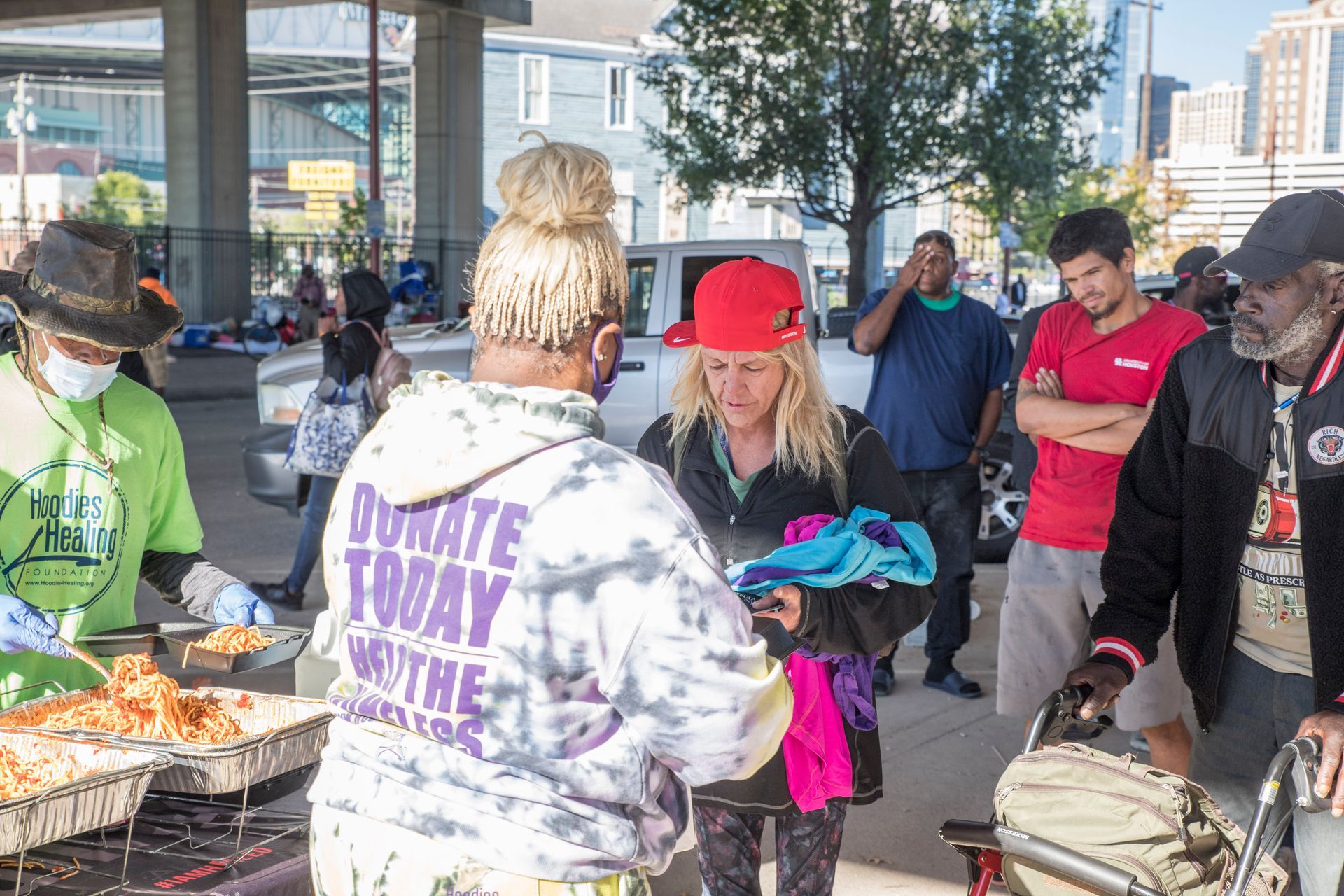 A group of people are standing around a table talking to each other.